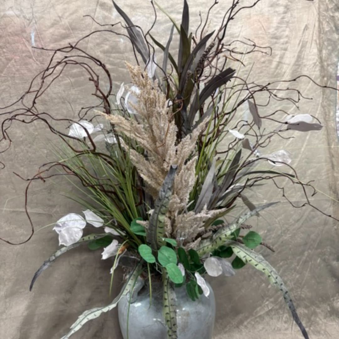 Tall arrangement of dried grasses and white accents in a gray vase