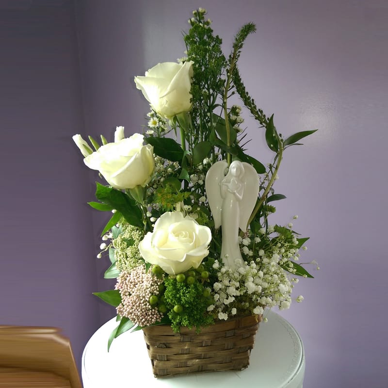 White roses in a basket with a small angel figurine
