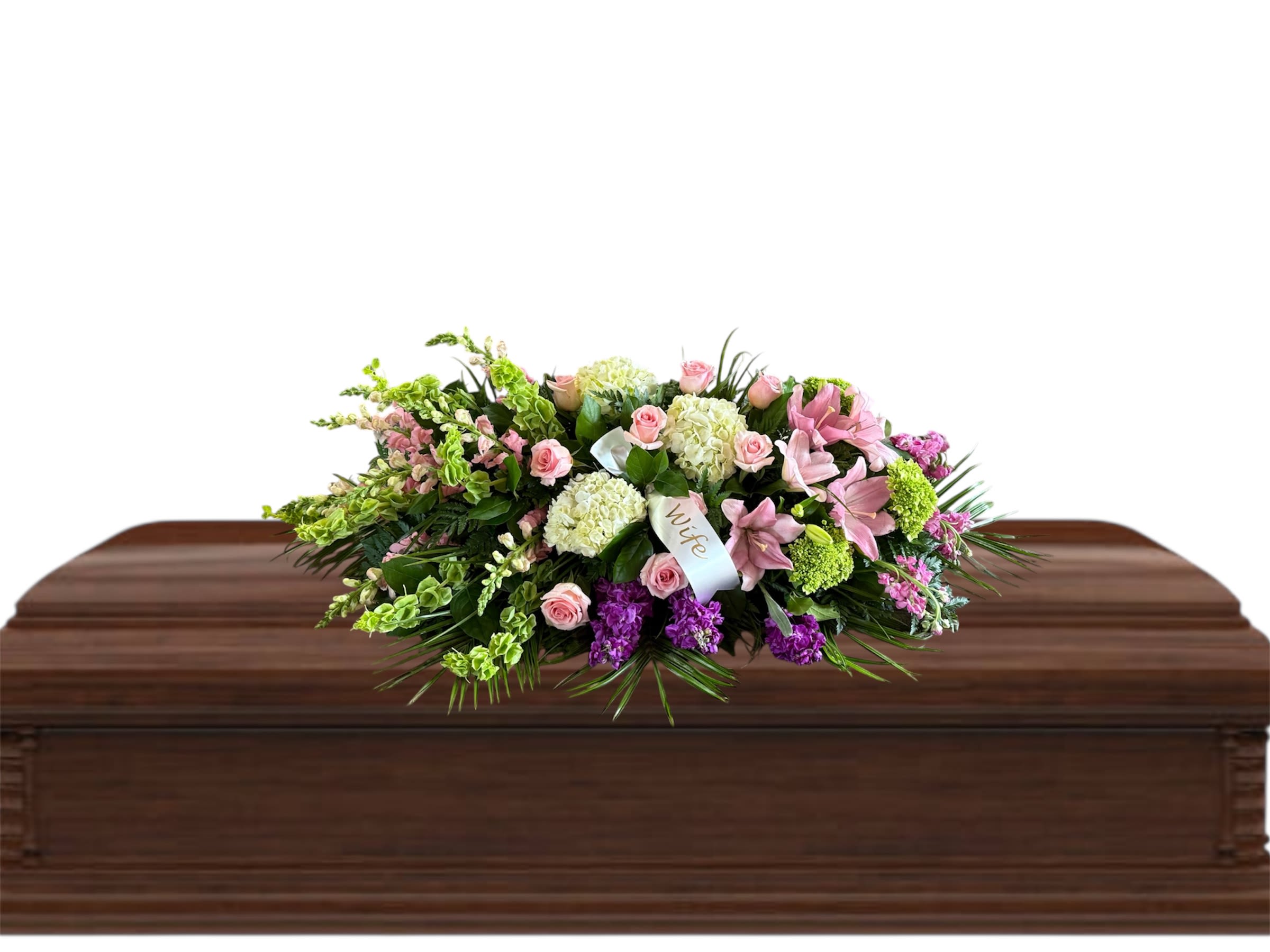 Pink and white floral casket spray on a wooden casket