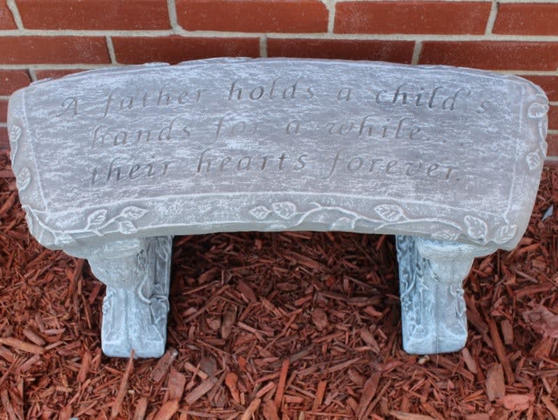 Decorative stone bench with an engraved quote in a garden bed
