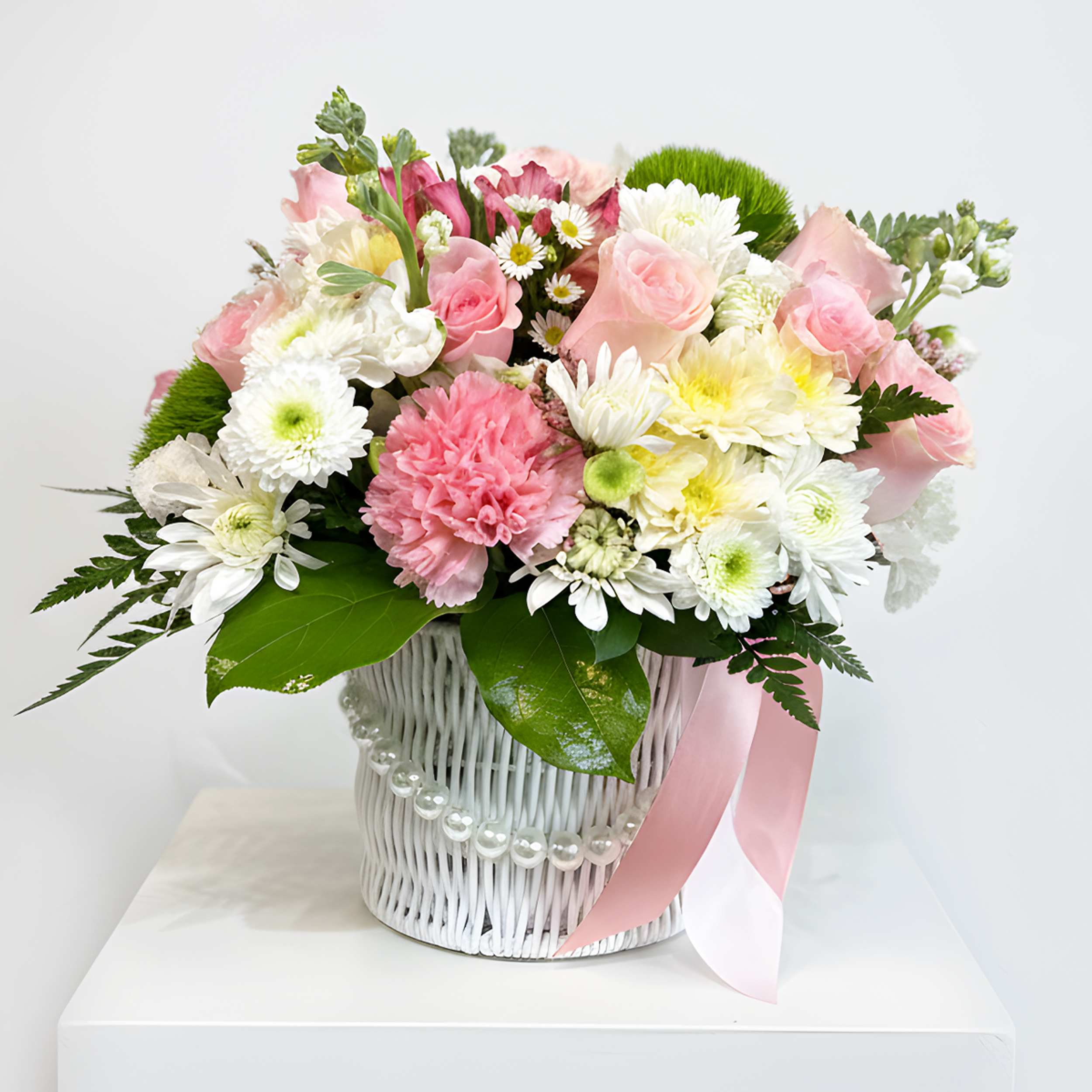 Pink and white mixed bouquet in a white basket with a pink ribbon