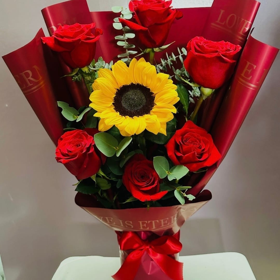 Bouquet of red roses and a yellow sunflower wrapped in red paper