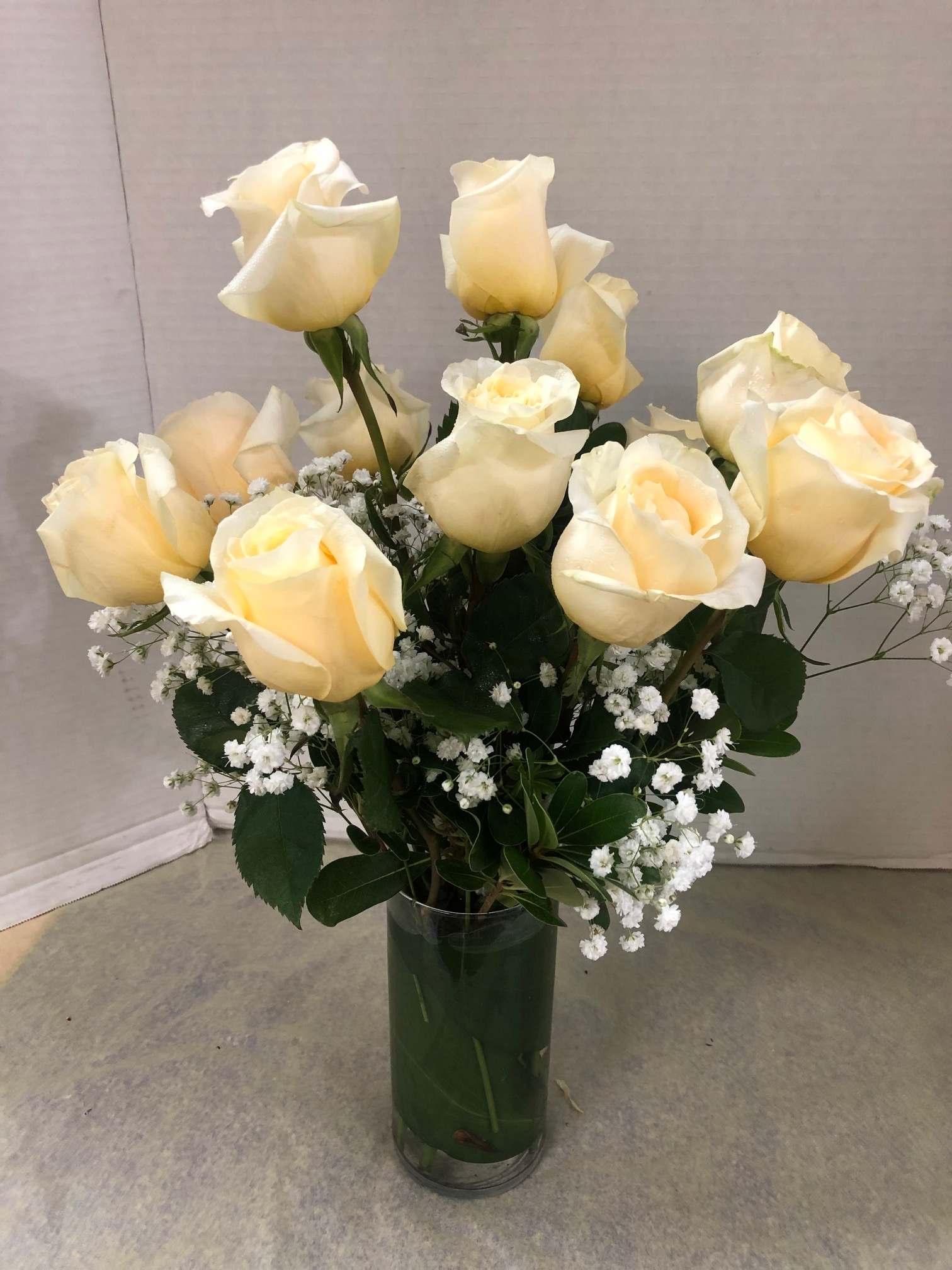 Cream roses arranged in a clear glass vase with small white filler flowers