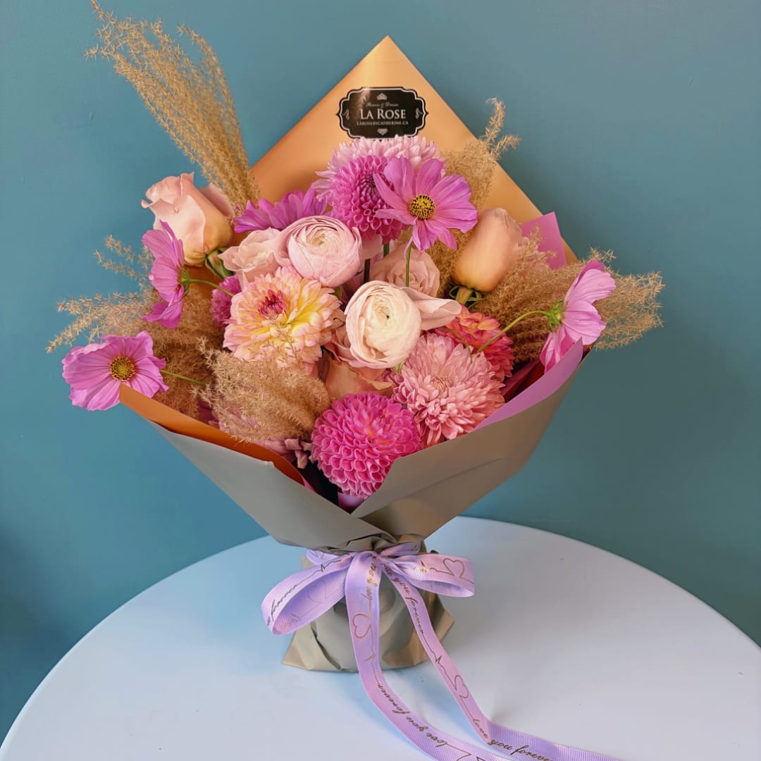 Pink and peach mixed bouquet wrapped in paper with a ribbon