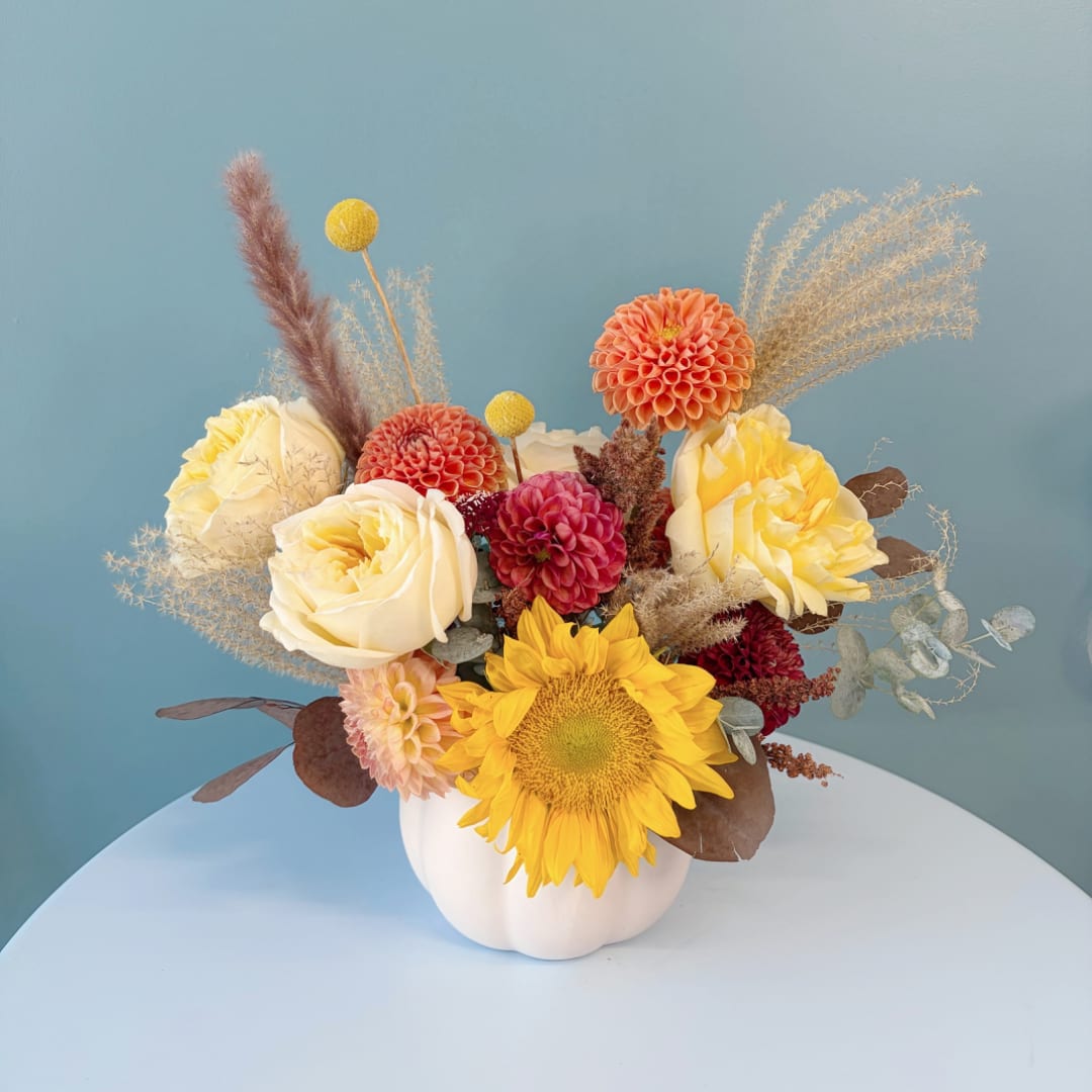 Mixed bouquet in a white vase with sunflowers, roses, and dahlias