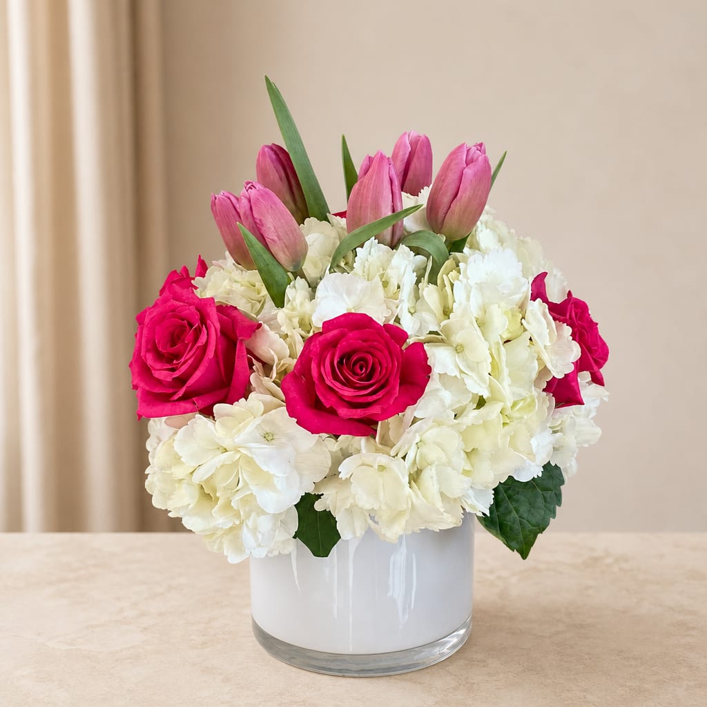 Pink tulips and hot pink roses in a white vase with white hydrangeas