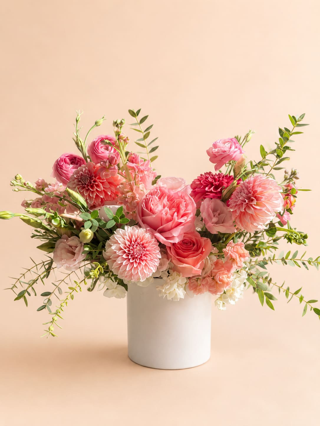 Pink floral arrangement in a white vase with roses and dahlias