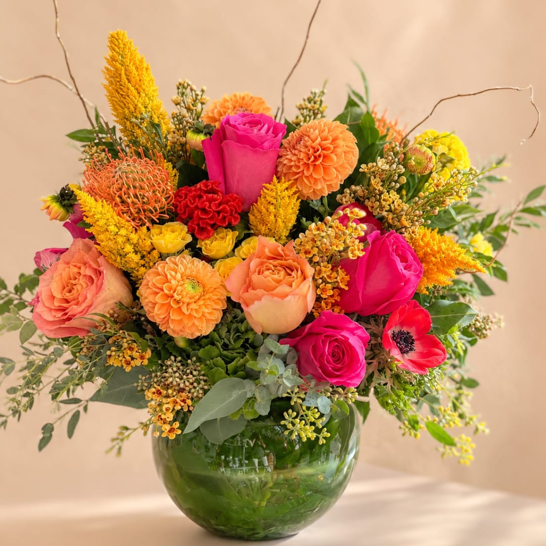 Bright mixed bouquet in a glass vase with pink, orange, and yellow blooms