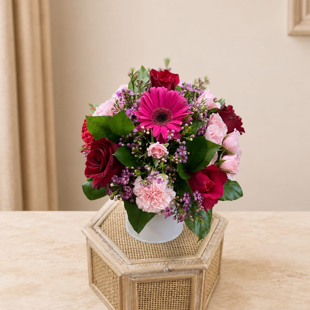 Pink and red mixed flower arrangement in a white vase