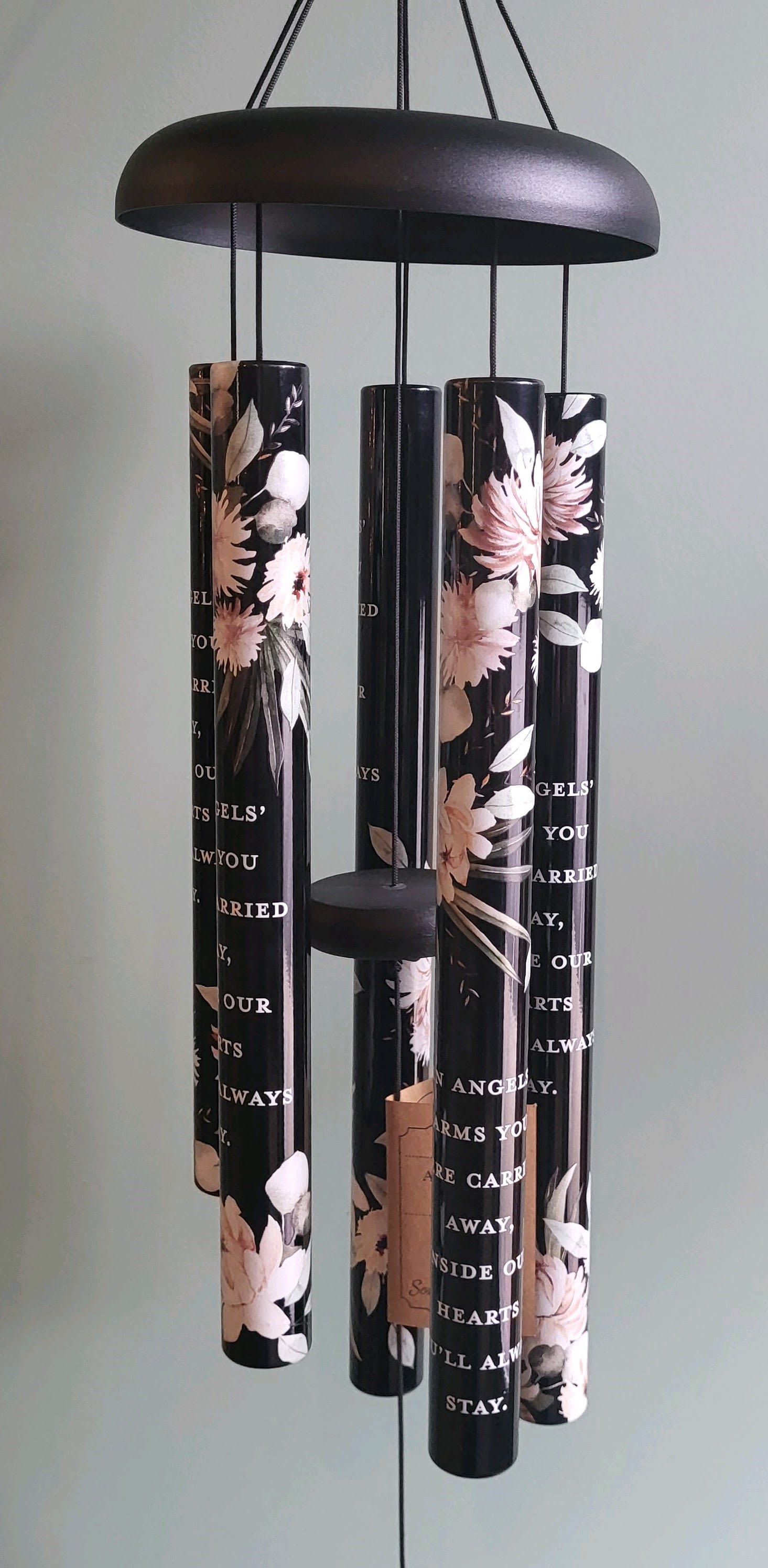 Black hanging wind chime with floral-printed tubes and a round top