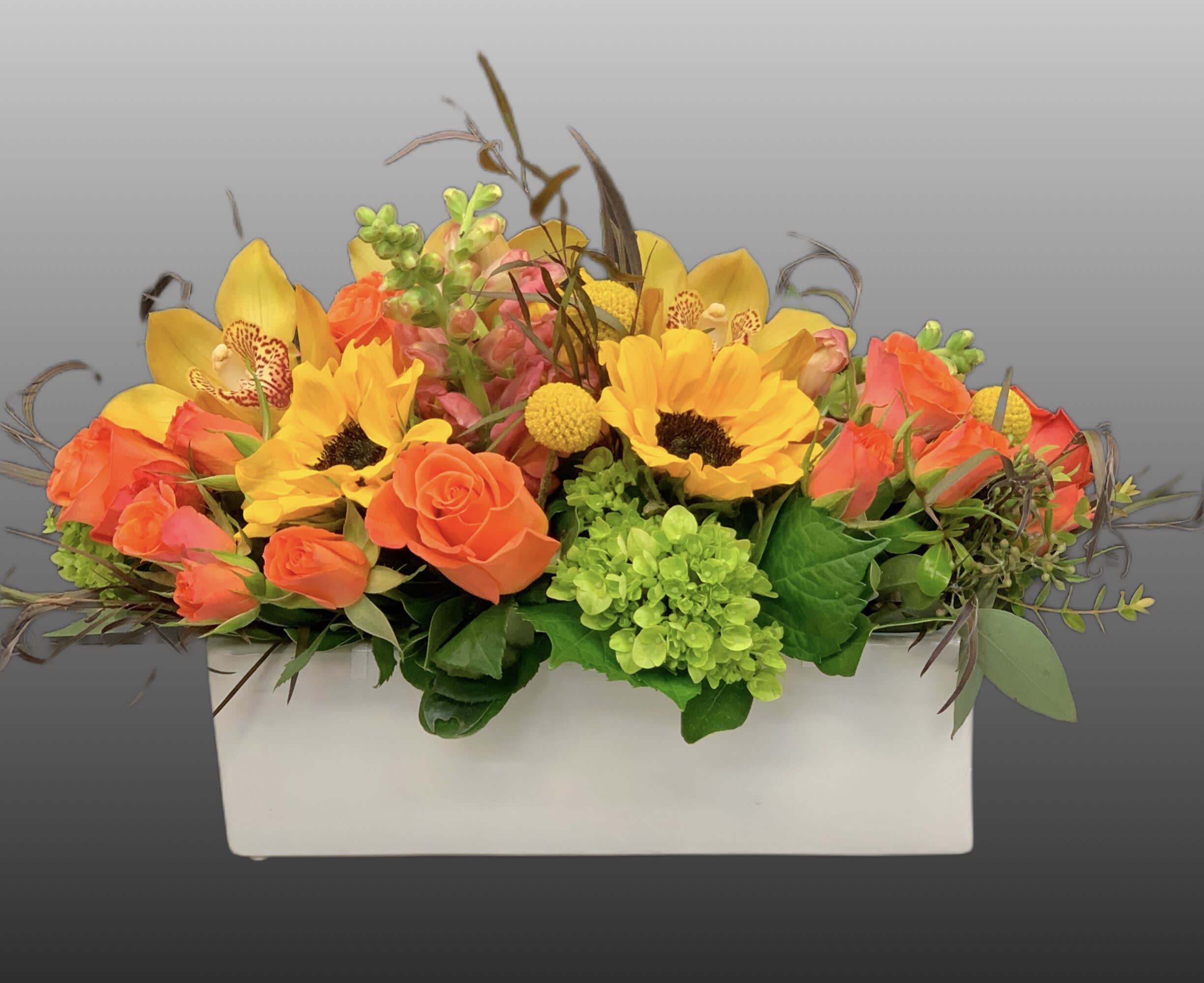 Bright mixed flower arrangement in a white rectangular container