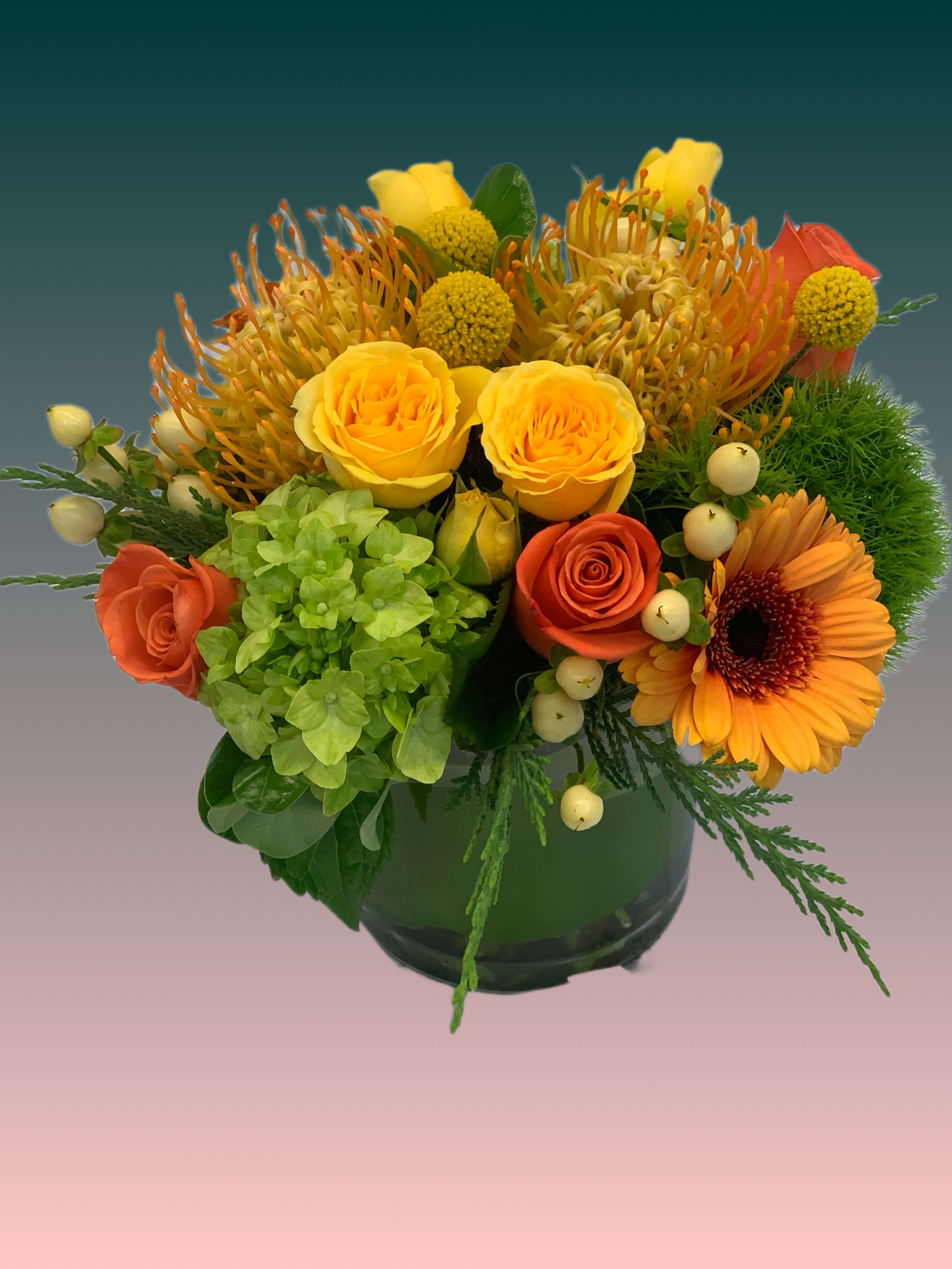 Bright mixed bouquet in a dark glass vase with yellow and orange blooms