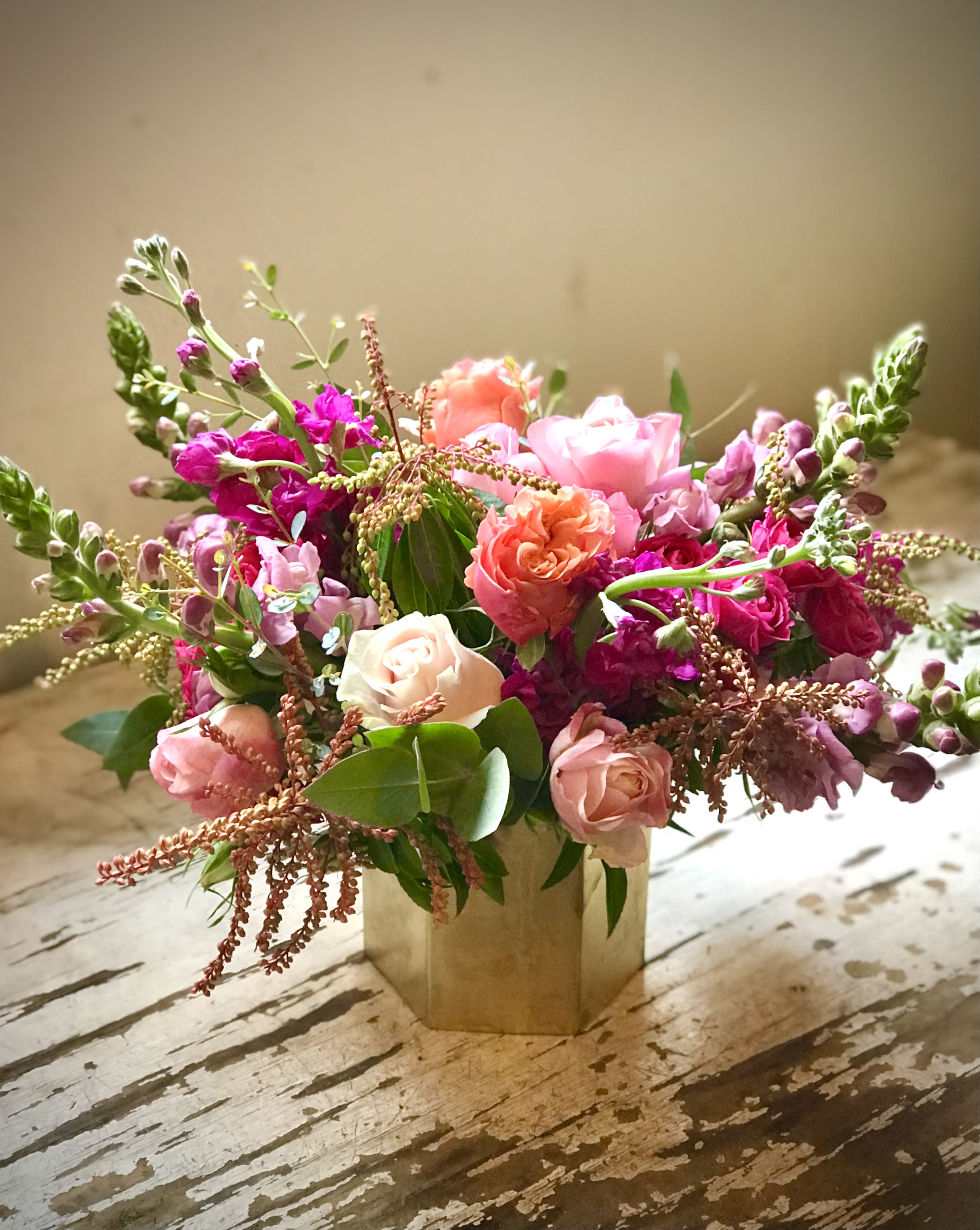 Pink and coral roses arranged in a gold vase