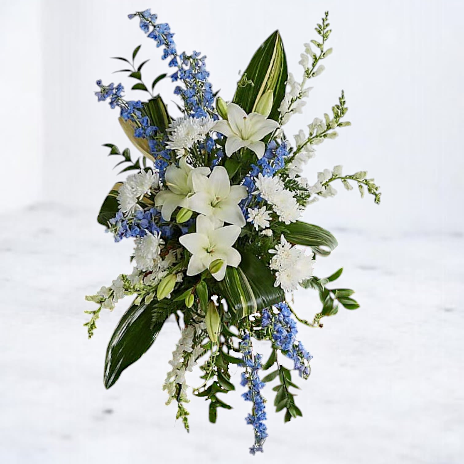 White lilies with blue and white flowers in a cascading arrangement