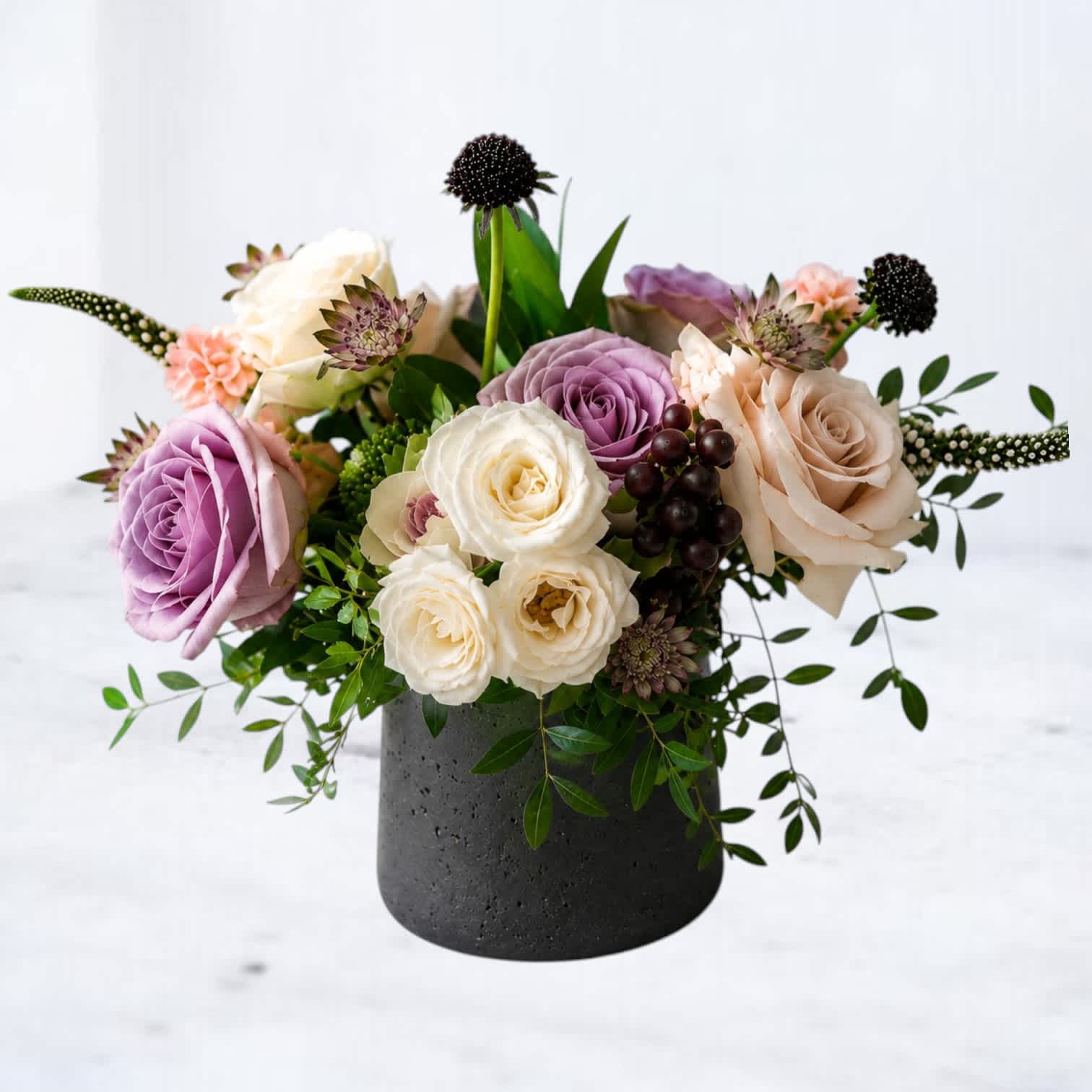 Mixed roses and small accent flowers arranged in a black vase