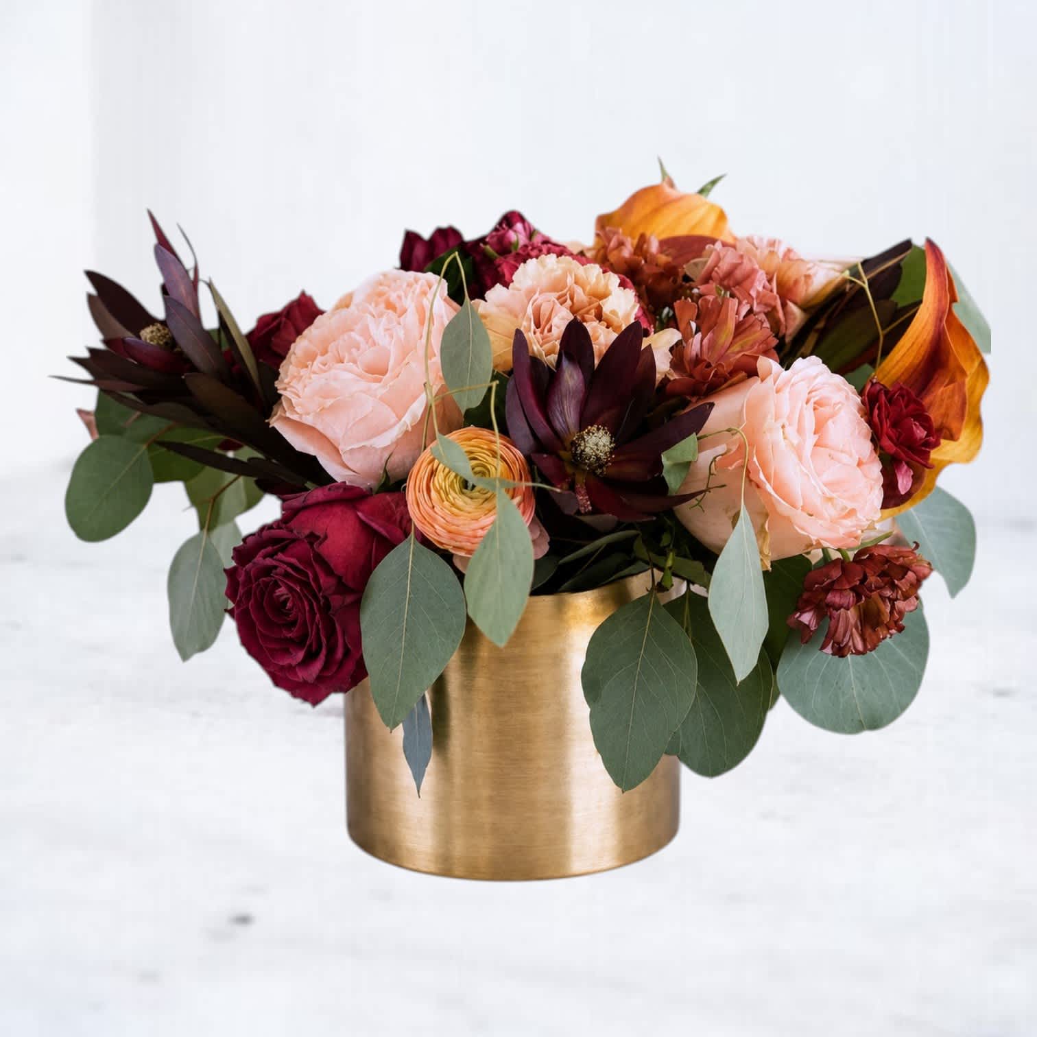 Bouquet of peach and burgundy flowers in a gold vase