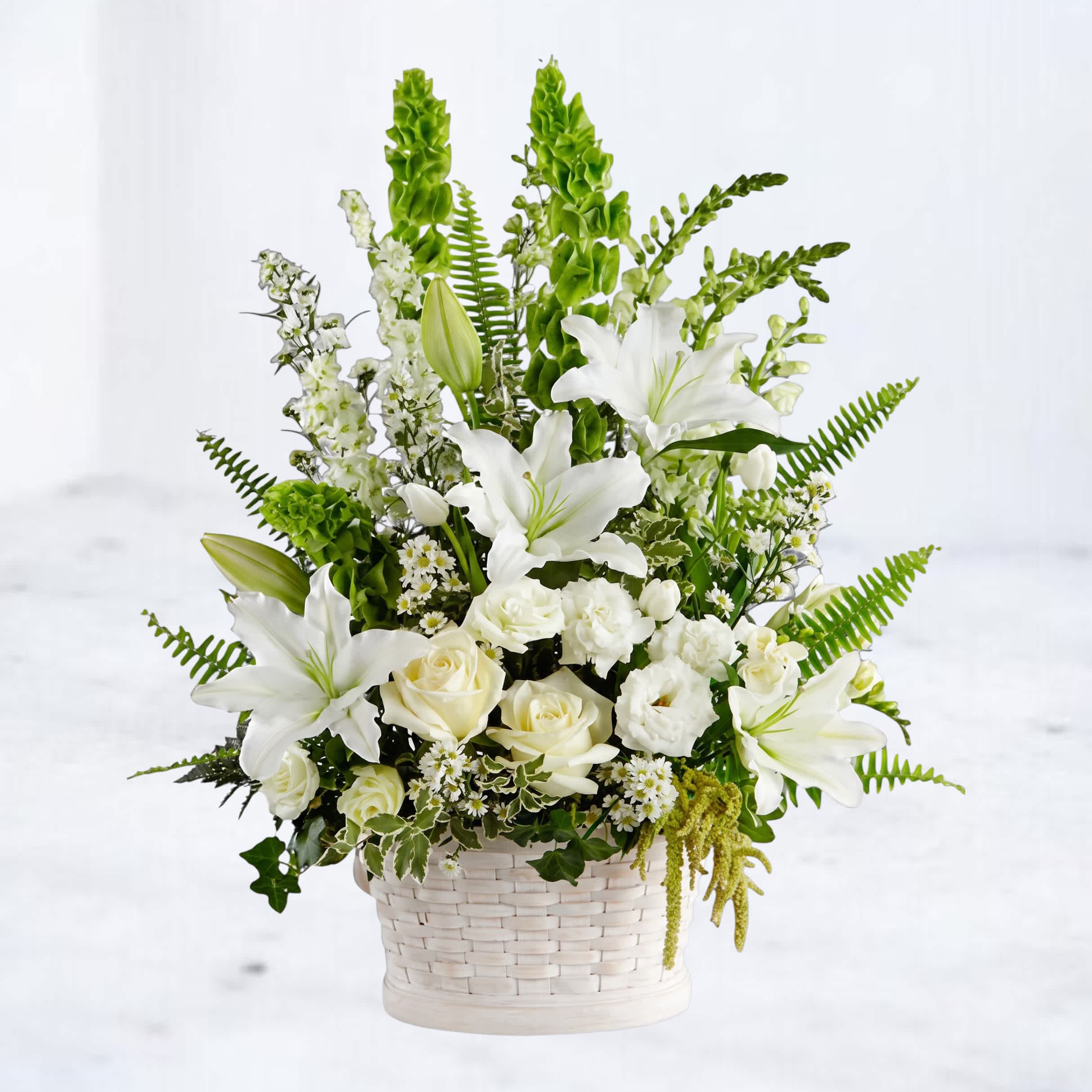 White lilies and roses in a white woven basket with green accents
