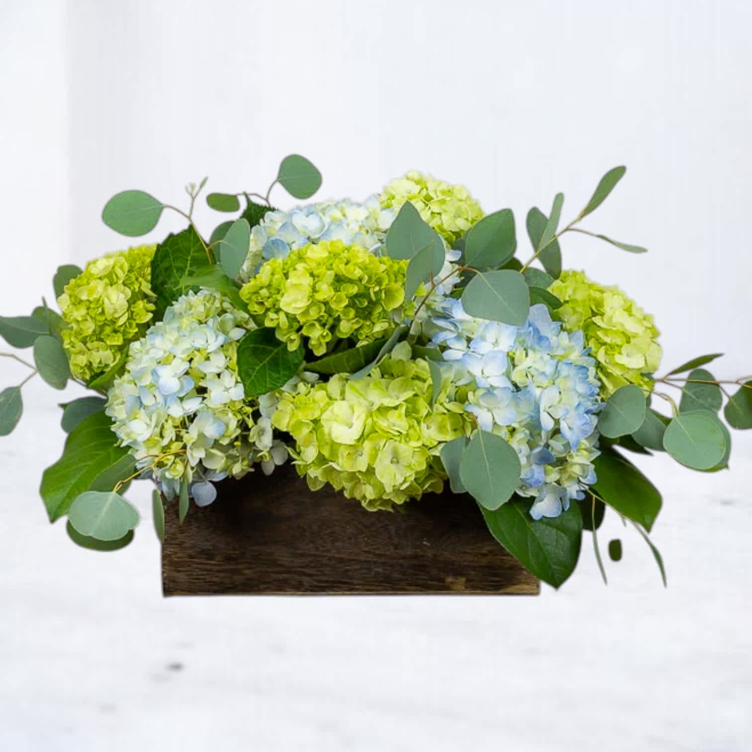 Low arrangement of blue and green hydrangeas in a wooden box