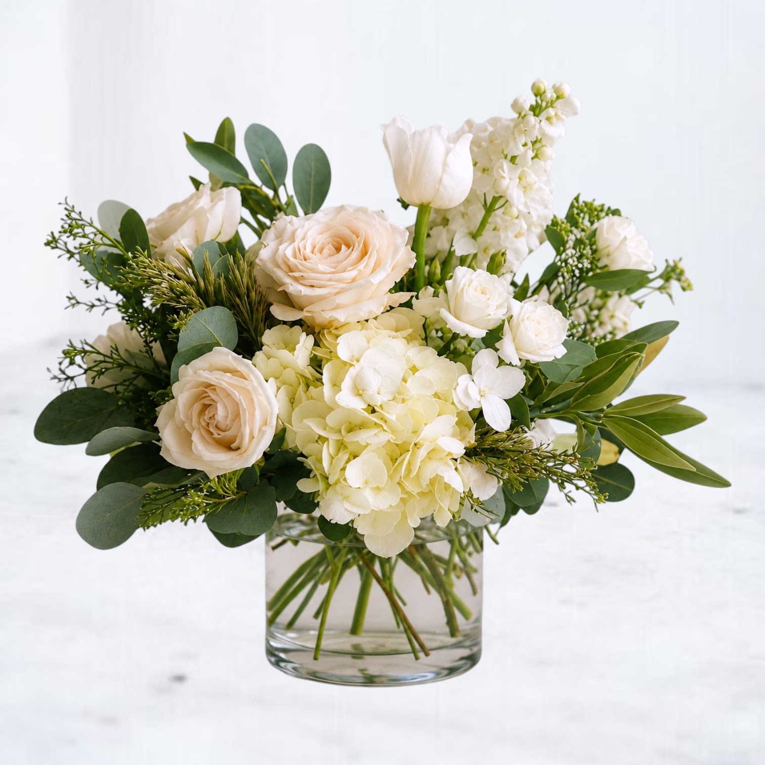 Linen Orchard - Linen Orchard is a refined garden-style arrangement featuring soft roses, hydrangea, and delicate white blooms layered with fresh eucalyptus and seasonal greenery. Designed in a clear glass vase, this arrangement highlights natural texture and an airy neutral palette.  With its soft linen tones and organic structure, Linen Orchard is perfect for birthdays, thank-you gifts, anniversaries, or simply bringing fresh floral beauty into the home.  Whiskey Wallflower is a design-forward florist serving Magnolia, The Woodlands, Montgomery, Willis, Conroe, Spring, Tomball and surrounding Houston-area communities. We specialize in thoughtfully composed, modern floral arrangements with a focus on premium blooms, intentional design, and reliable same-day delivery. Every piece is created with care to make life’s moments feel elevated, personal, and unforgettable.