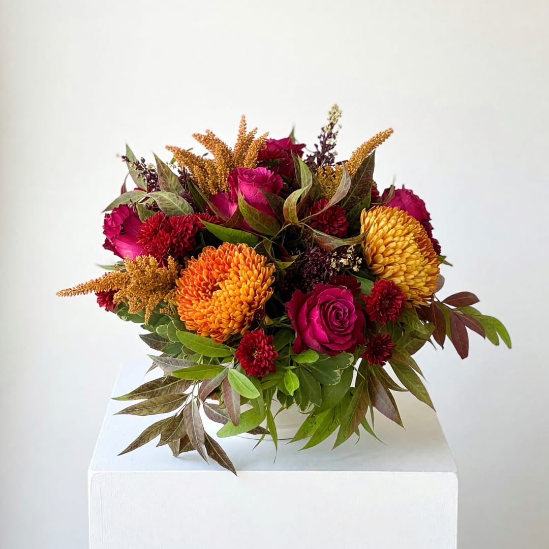 Bouquet of magenta roses and orange chrysanthemums with autumn foliage