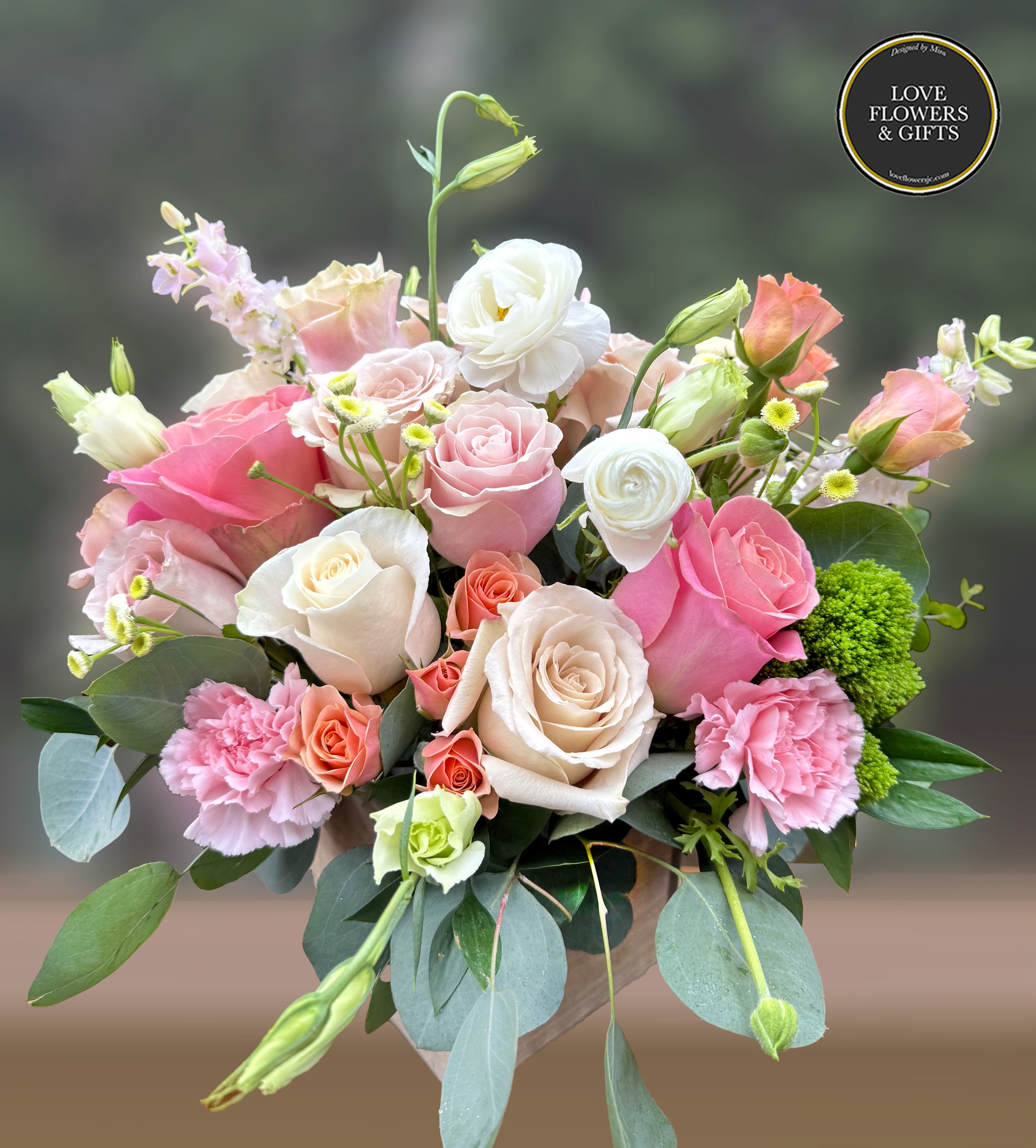 Mixed bouquet of pink and cream roses with carnations and lisianthus in a vase