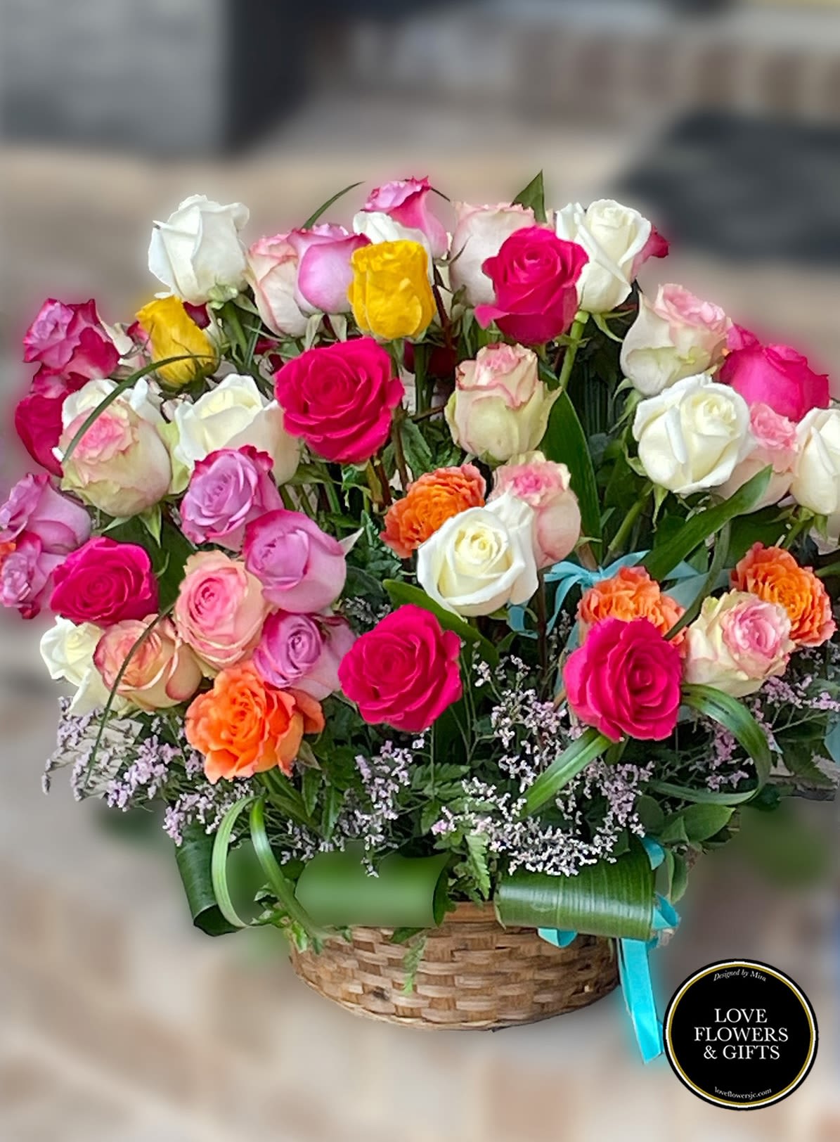 Basket arrangement of bright pink, white, yellow, and orange roses with filler flowers