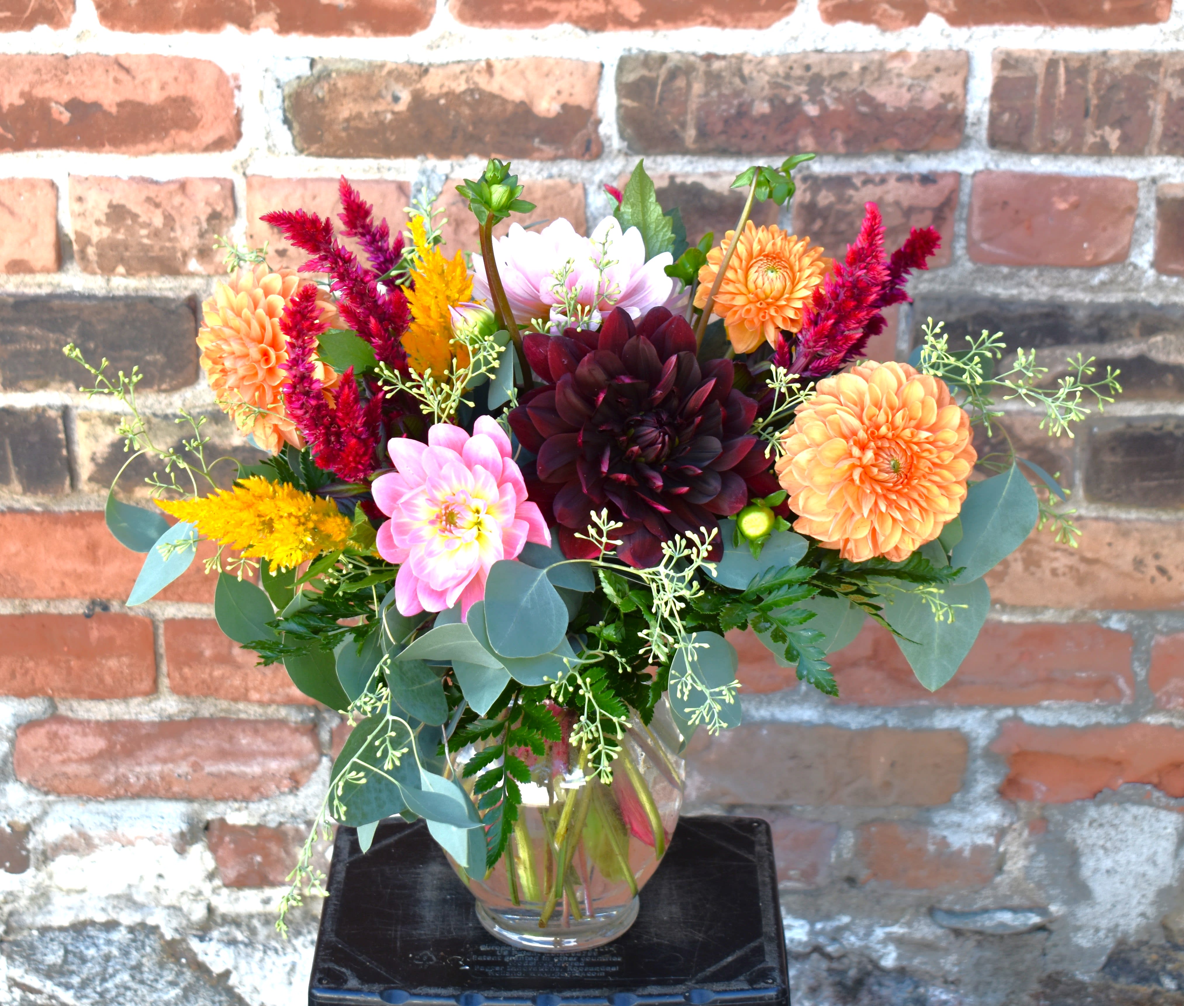 Mixed bouquet of dahlias and colorful filler flowers in a clear glass vase