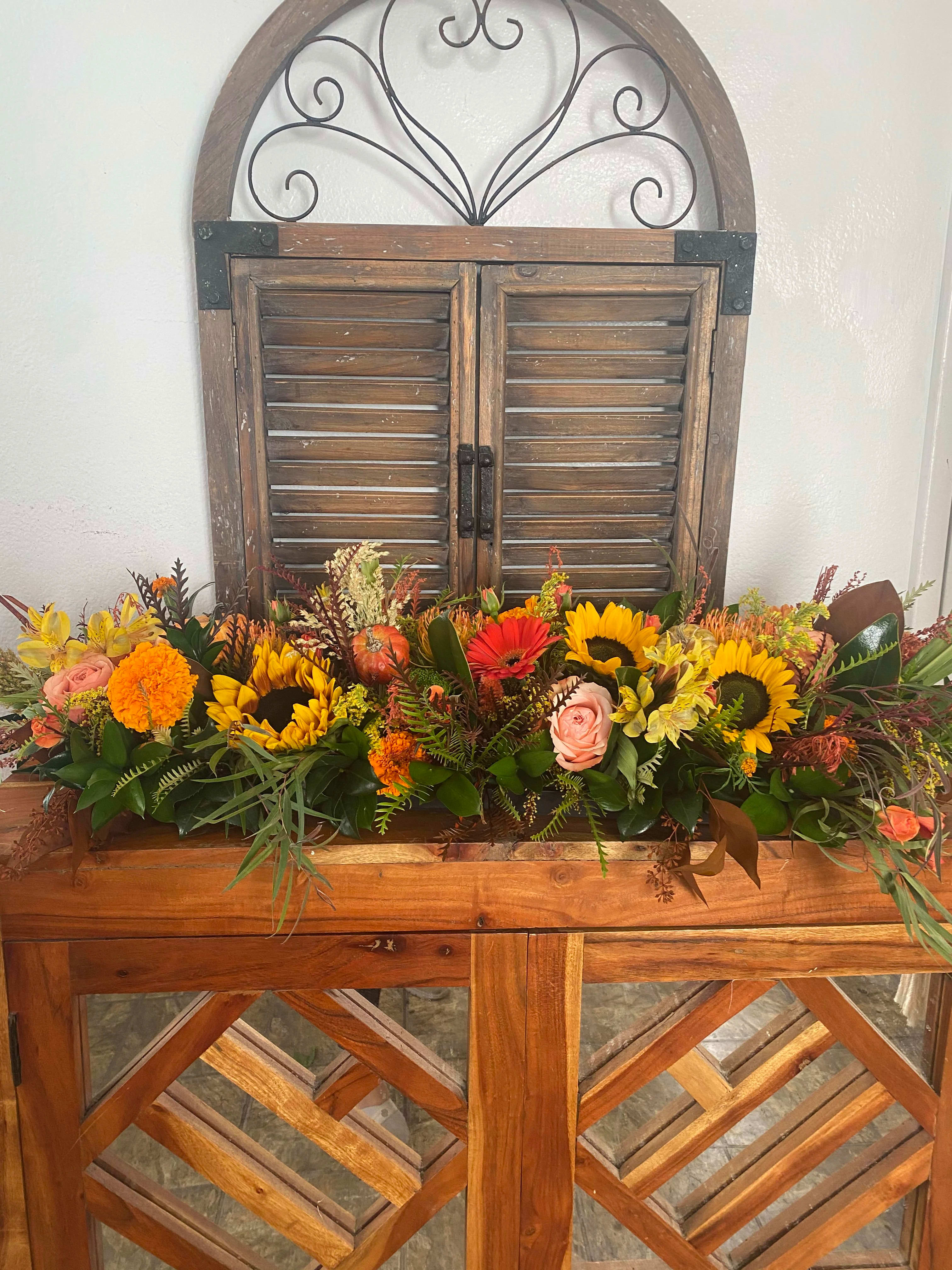 Long autumn floral arrangement with sunflowers, roses, and marigolds in a wooden container