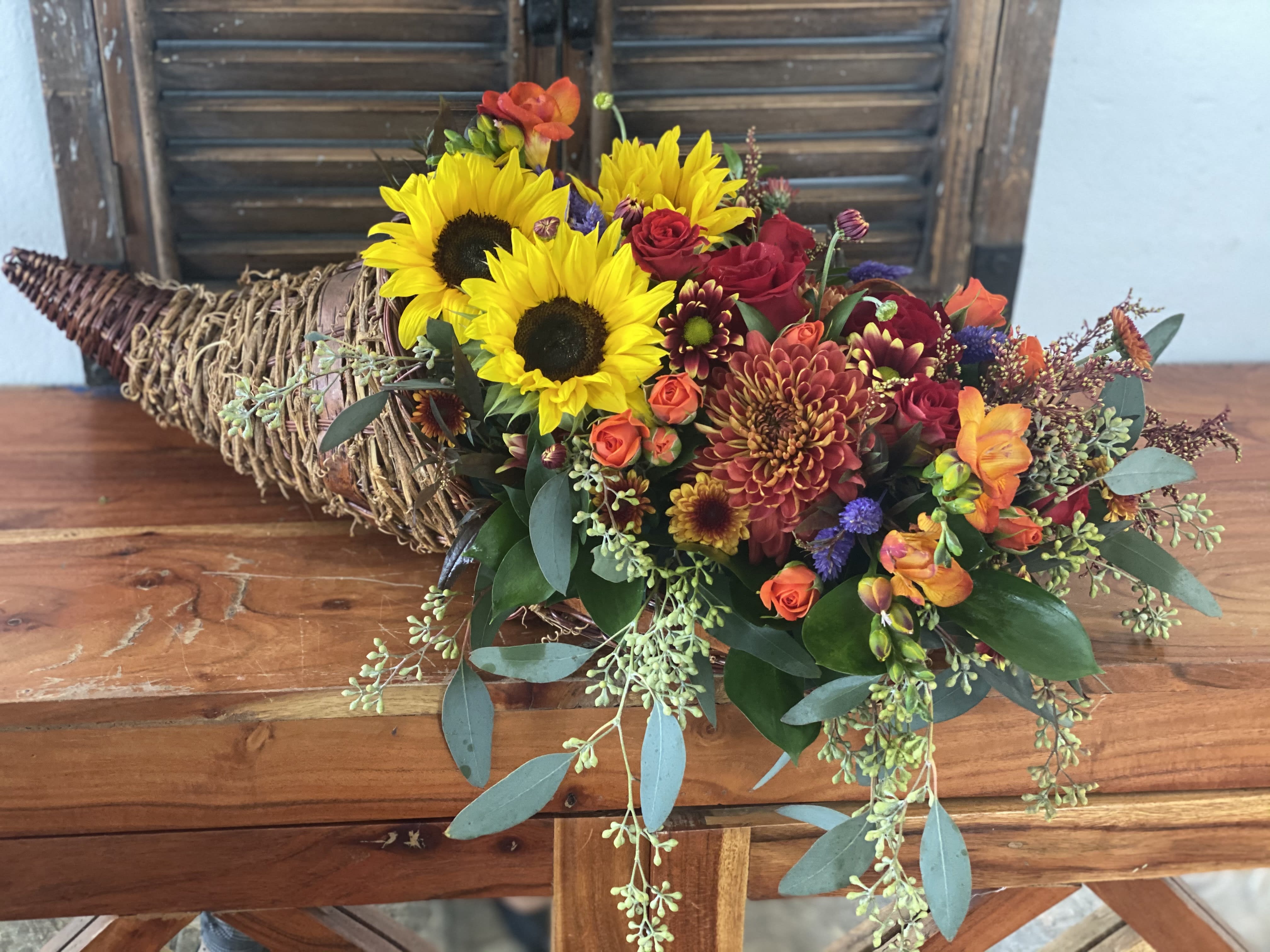 Mixed bouquet with sunflowers, roses, and chrysanthemums in a woven wrap