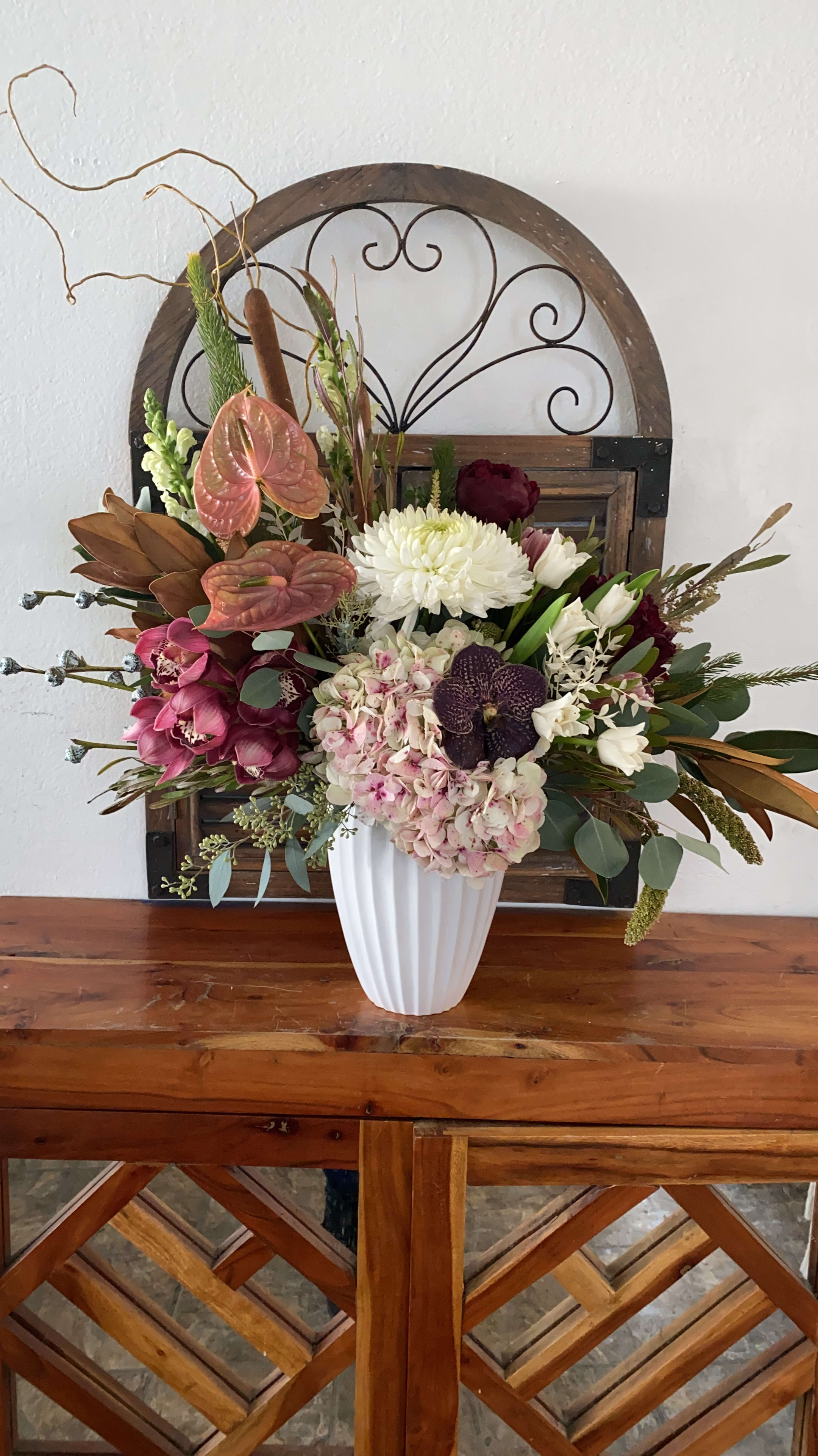 Mixed floral arrangement in a white vase with pink, white, and burgundy blooms