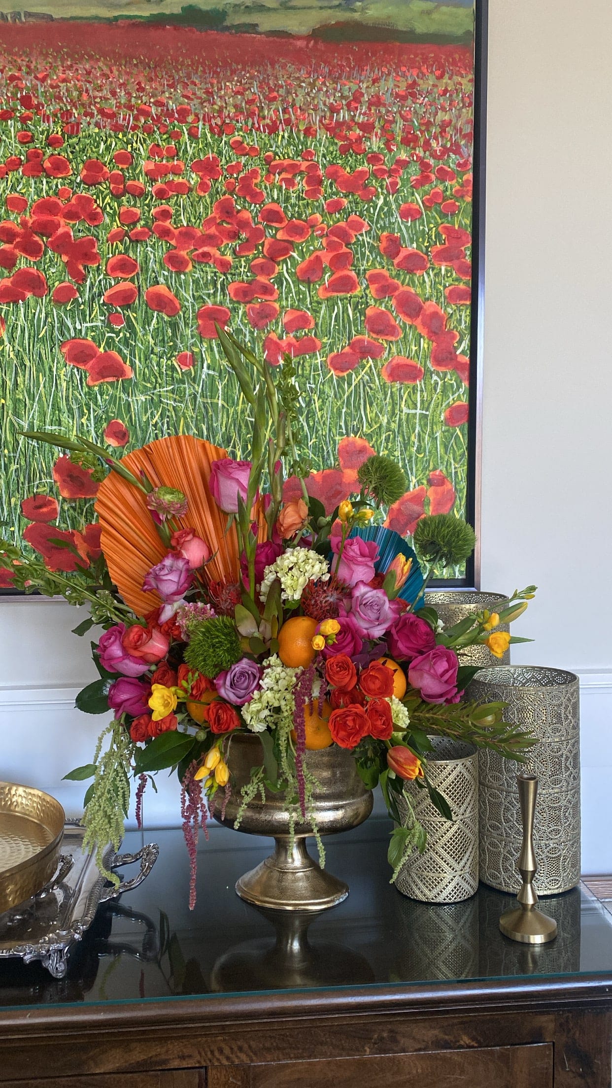 Colorful floral arrangement in a gold pedestal vase with roses and oranges