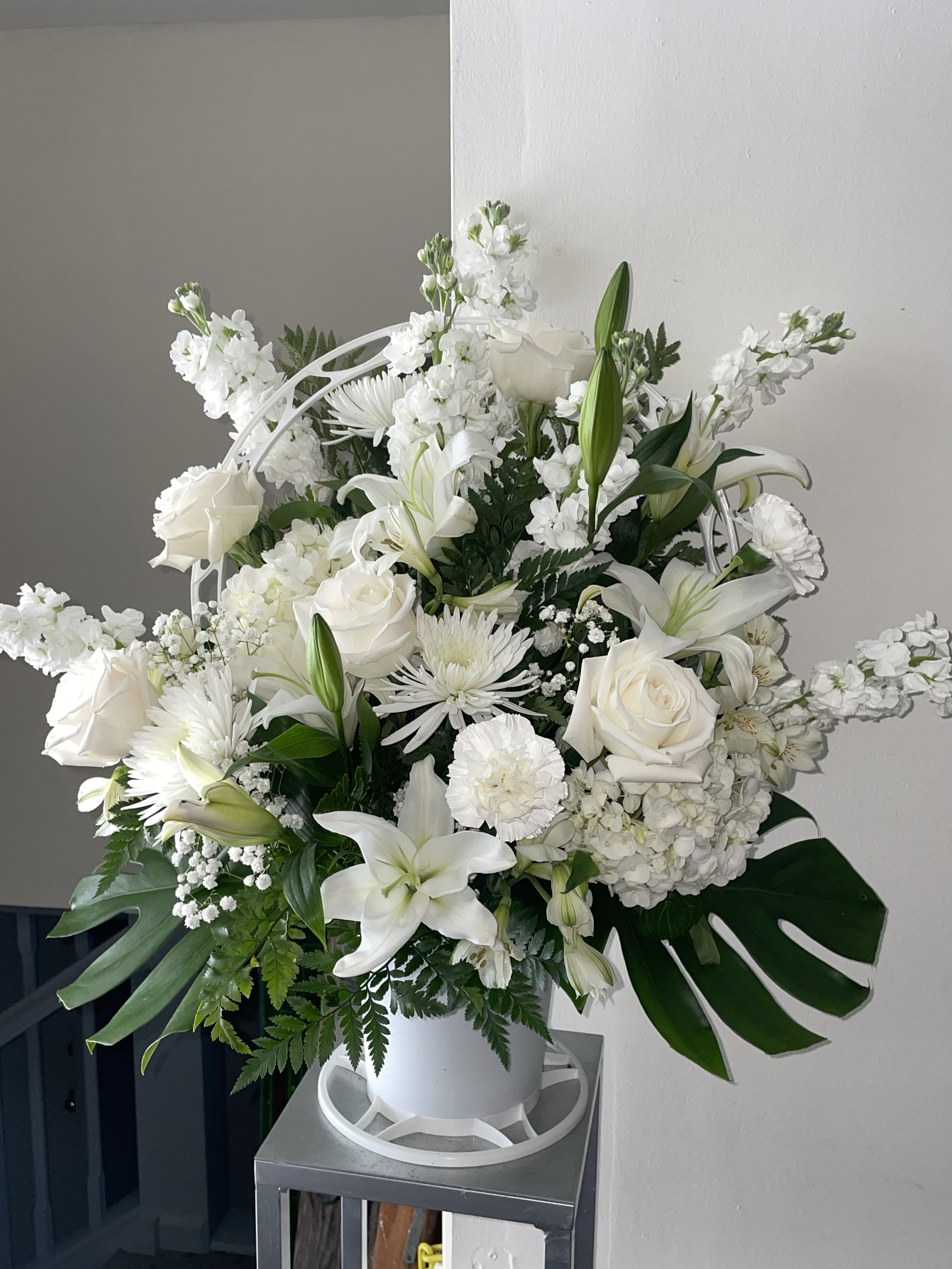 Peaceful Sympathy Basket - A large, upright sympathy arrangement that reads as quietly elegant and deeply respectful - perfect as a sympathy arrangement or memorial tribute. The Peaceful Sympathy Basket pairs classic white lilies and roses with chrysanthemums and carnations to create a serene, formal centerpiece that communicates comfort and reverence to the person you're honoring.  Ideal for sending condolences, expressing sympathy after a loss, or as a tasteful offering at a memorial or funeral, this arrangement conveys calm and support to grieving families. Its large size and upright form make it suitable for display on altars or entry tables; please let us know service details for timely delivery and we'll ensure it arrives fresh and respectfully presented.