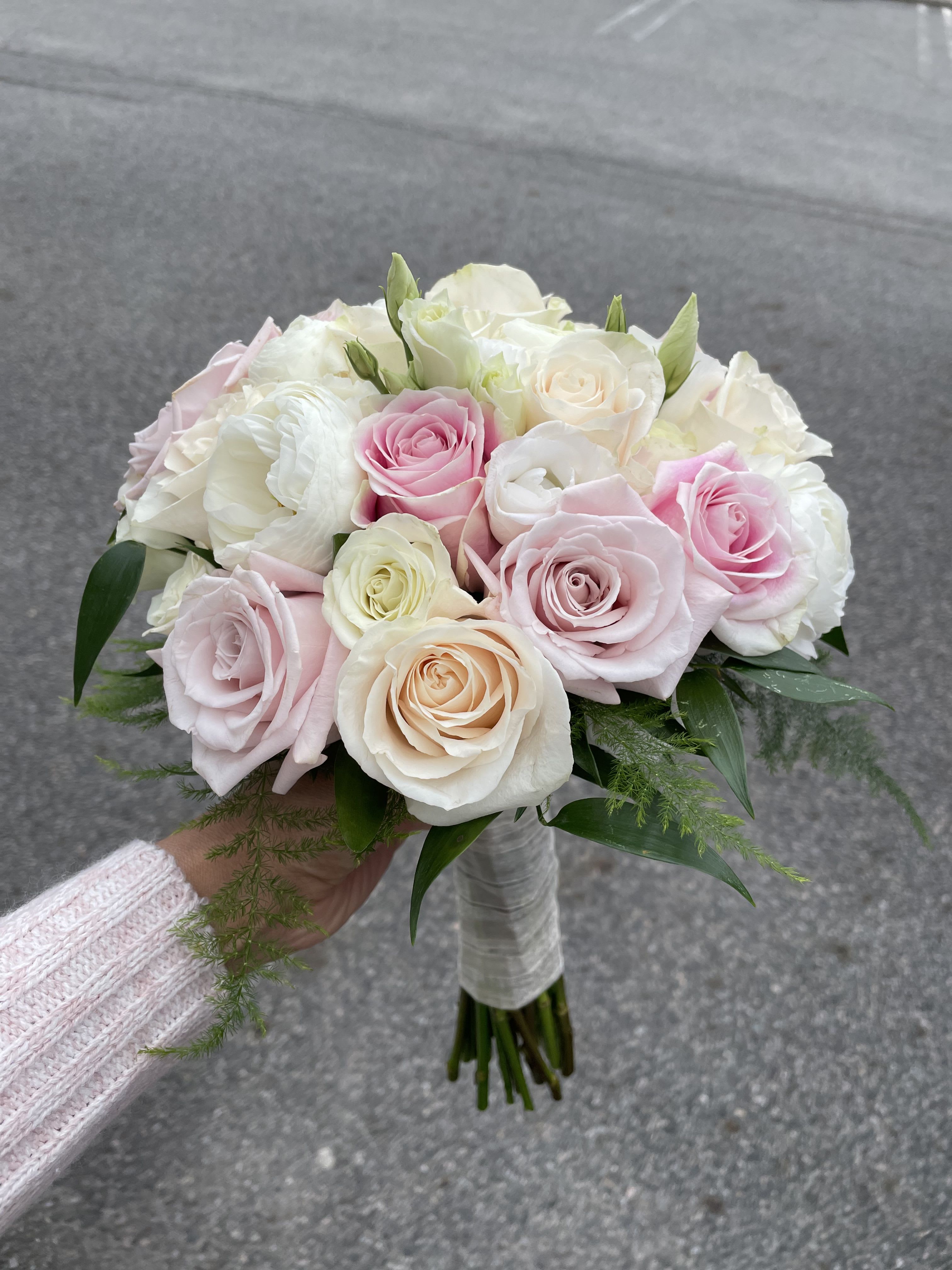 Make You Blush Wedding Bouquet - Rounded clusters of blush pink, pale and soft white roses create an instantly romantic wedding bouquet that reads tender and timeless - perfect as a bridal bouquet or for a wedding party. This flowers for weddings arrangement frames the bride with airy pastels and delicate texture, the kind of bouquet that makes her feel cherished and beautifully seen on the aisle.  Ideal for brides, bridesmaids, anniversaries, or as a thoughtful personal gift, this bouquet suits garden, rustic, and classic ceremonies alike. To keep the roses looking their best, keep stems in water until the moment of use and store in a cool place away from direct sunlight; ordering options and size details are available at checkout to ensure the arrangement fits your wedding look.
