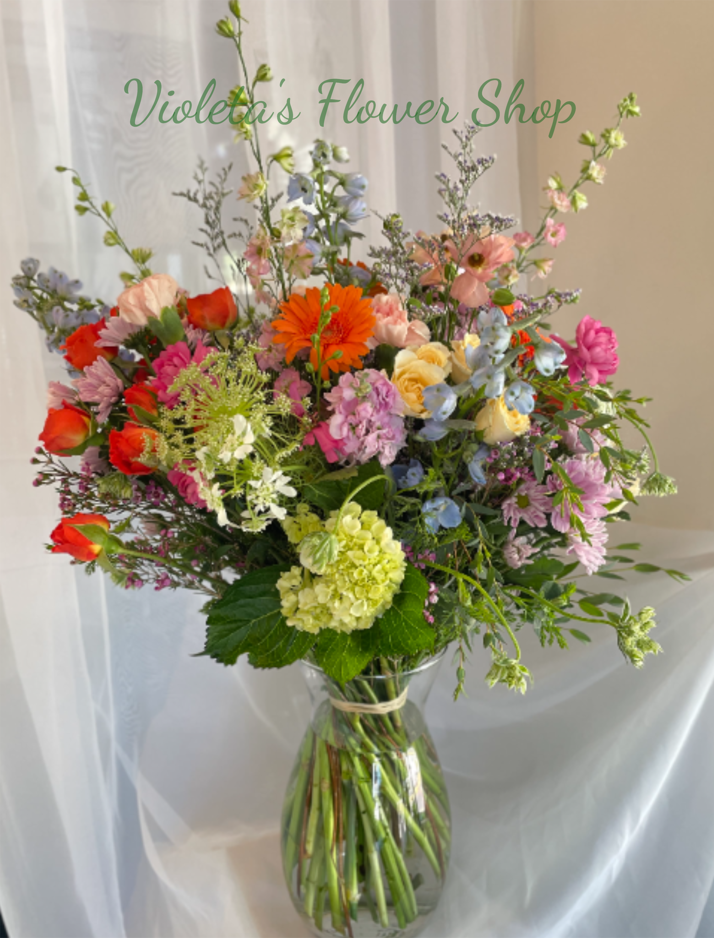Just Wild Blooms Arrangement - A loose, garden-style mixed bouquet that feels freshly gathered from a sunlit patch-this flower arrangement is perfect as a birthday bouquet, a thank-you gift, or a bright spring surprise. The airy silhouette, with taller stems rising above a lush center, gives the person you're thinking of a joyful, effortless impression: celebratory without being formal, lively without overpowering.  Made to make someone feel seen and celebrated, this arrangement suits recipients who love color, texture, and a casual garden vibe-mothers, friends, coworkers, or that special someone marking a small victory. Arrives ready to display in the included vase; trim stems and refresh water every few days to keep the mixed blooms looking their best.