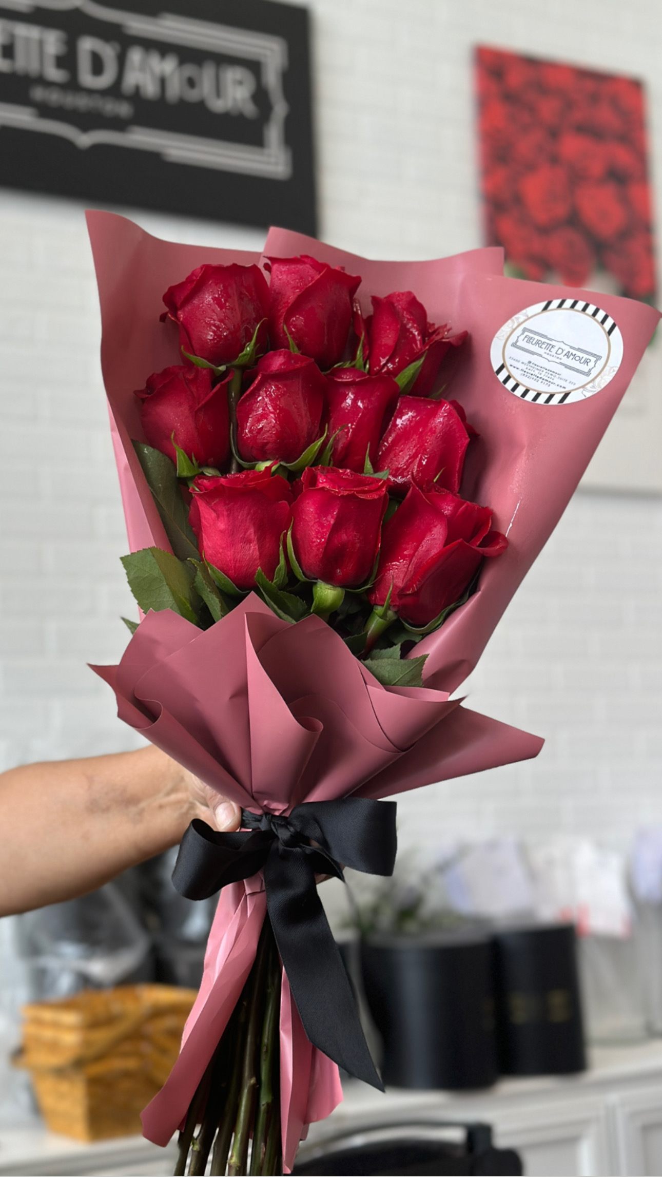 Bouquet of red roses wrapped in pink paper with a black ribbon