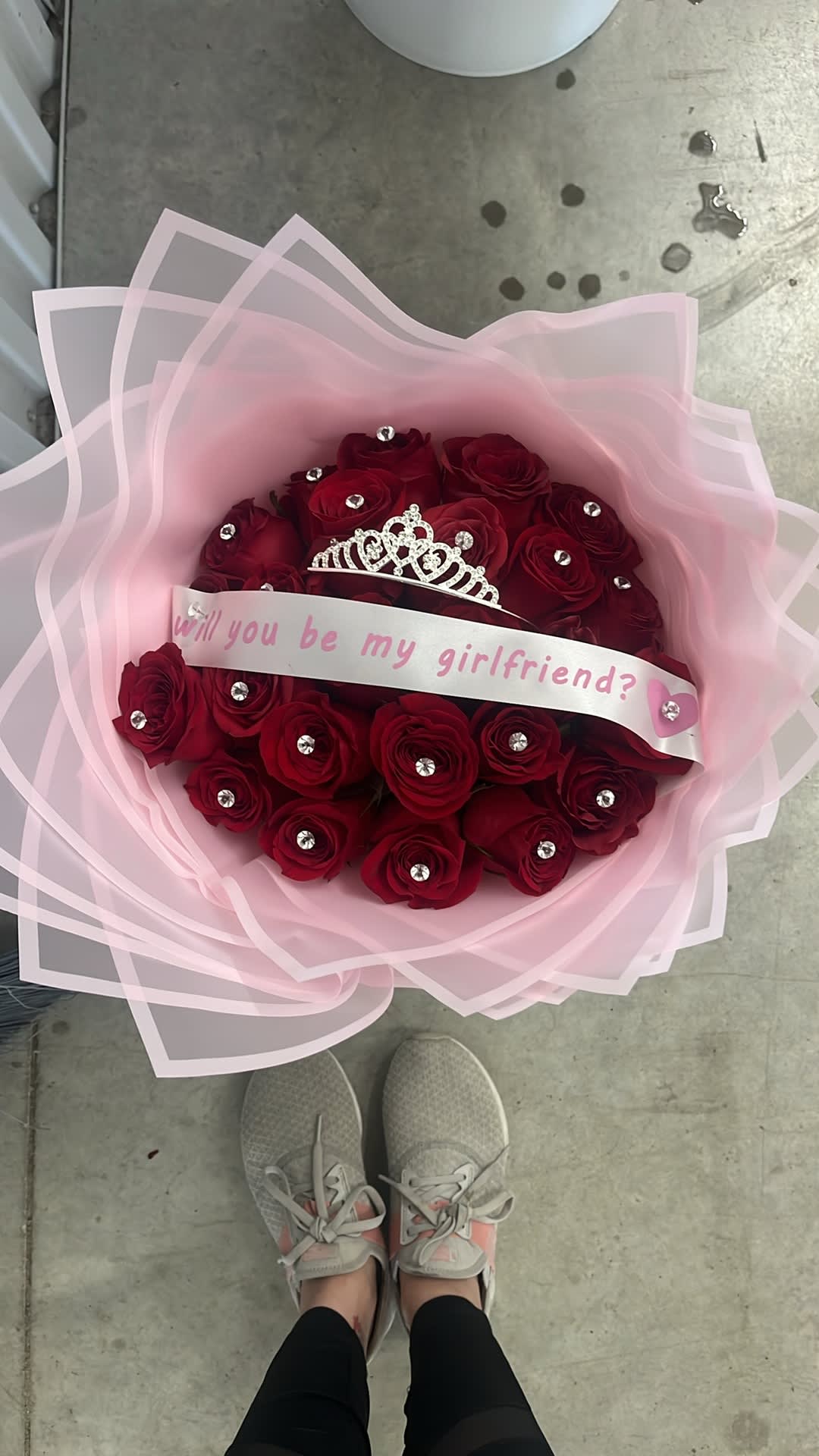 Bouquet of red roses wrapped in pink paper with a tiara and message ribbon