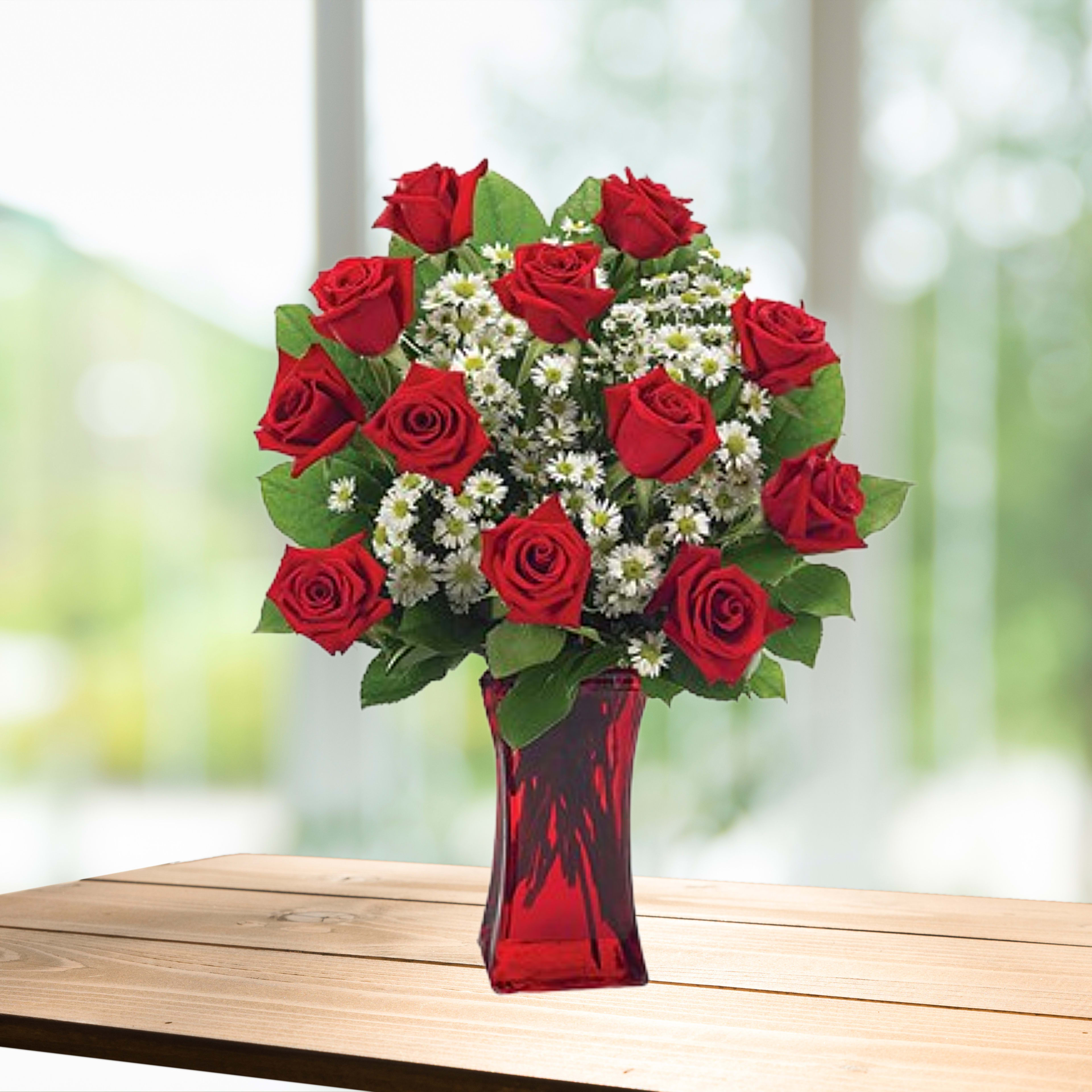 Red roses and white daisy-like flowers in a red glass vase