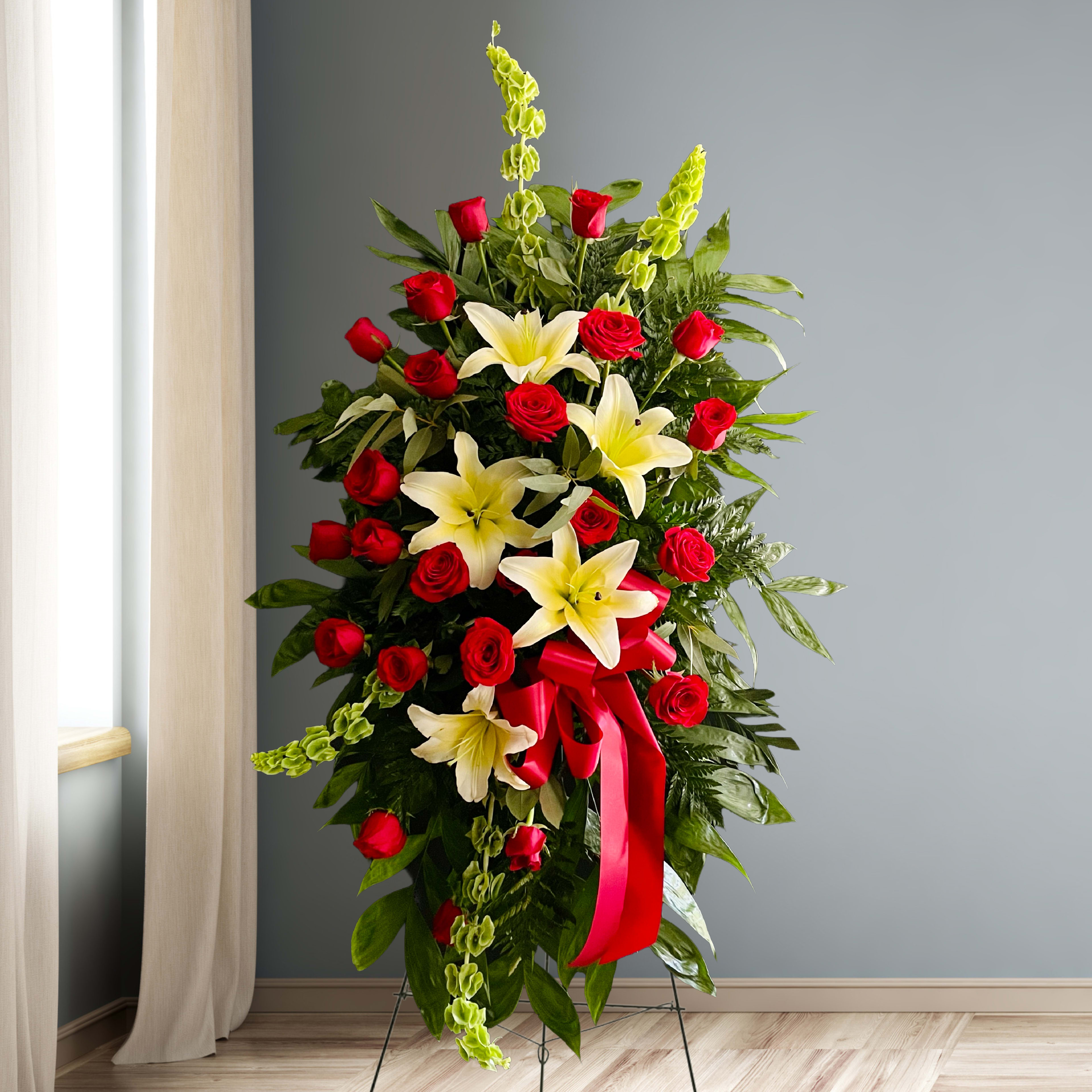 Standing floral spray with red roses, white lilies, and a red ribbon