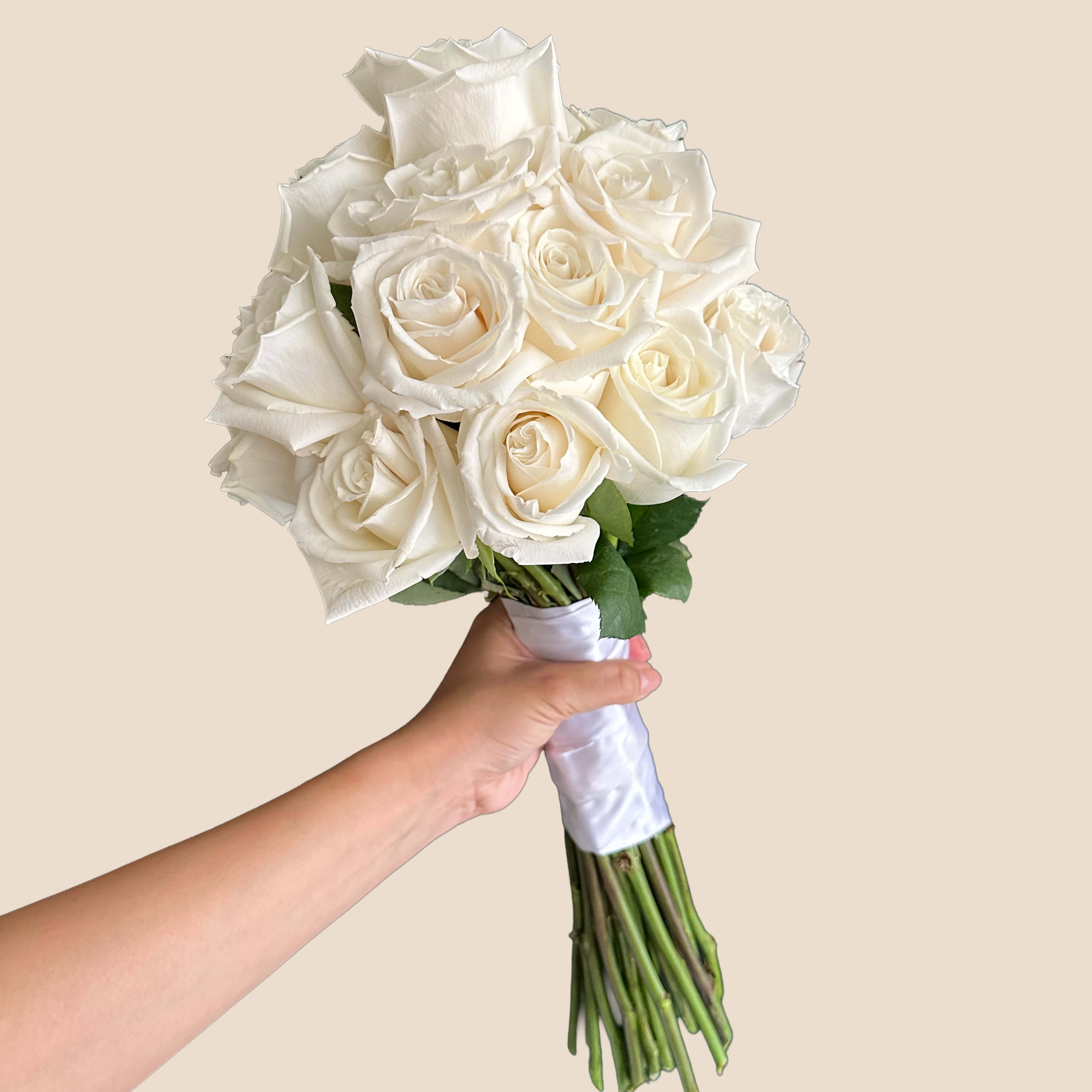 Handheld bouquet of white roses wrapped in white ribbon