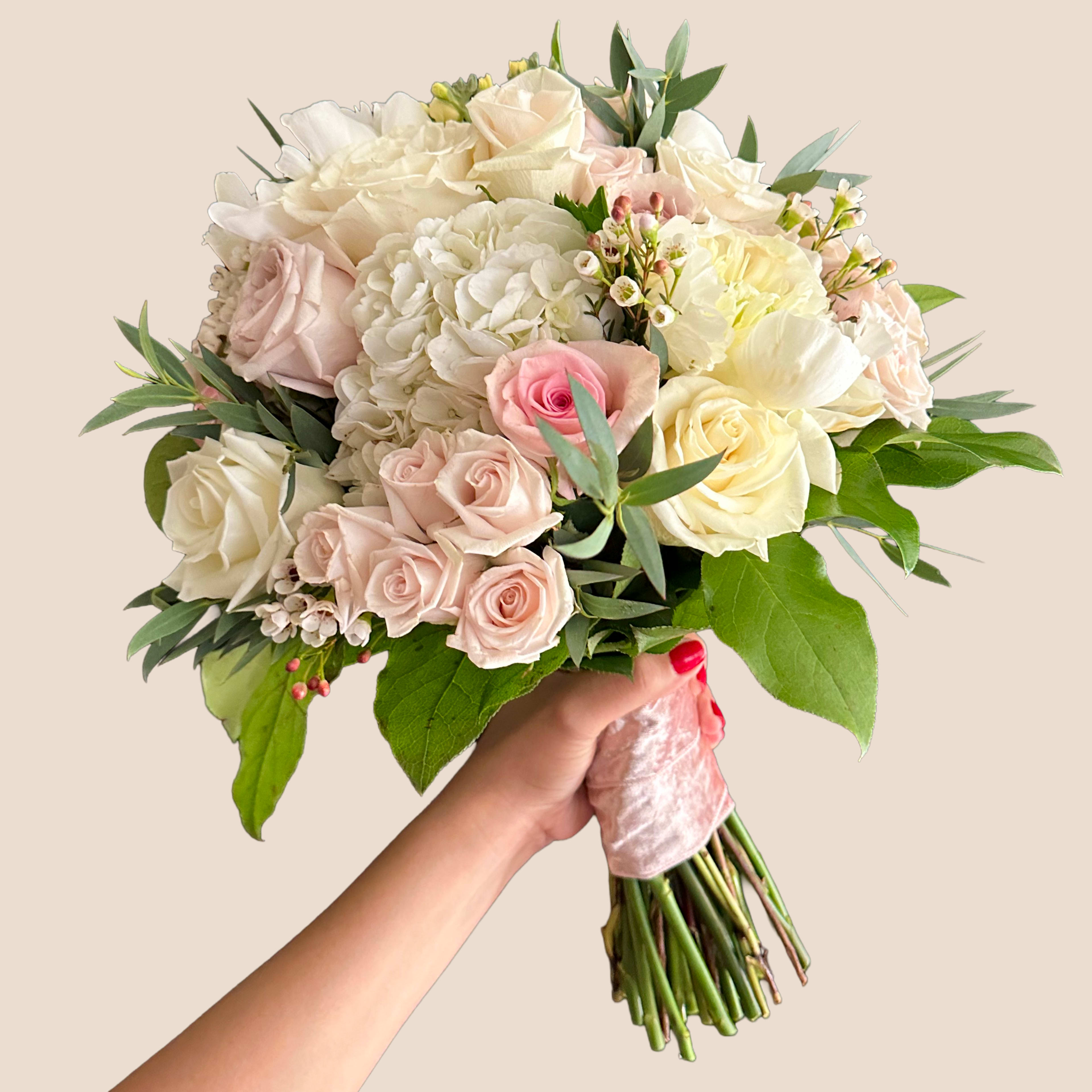 Handheld bouquet of pale roses and white hydrangeas with greenery