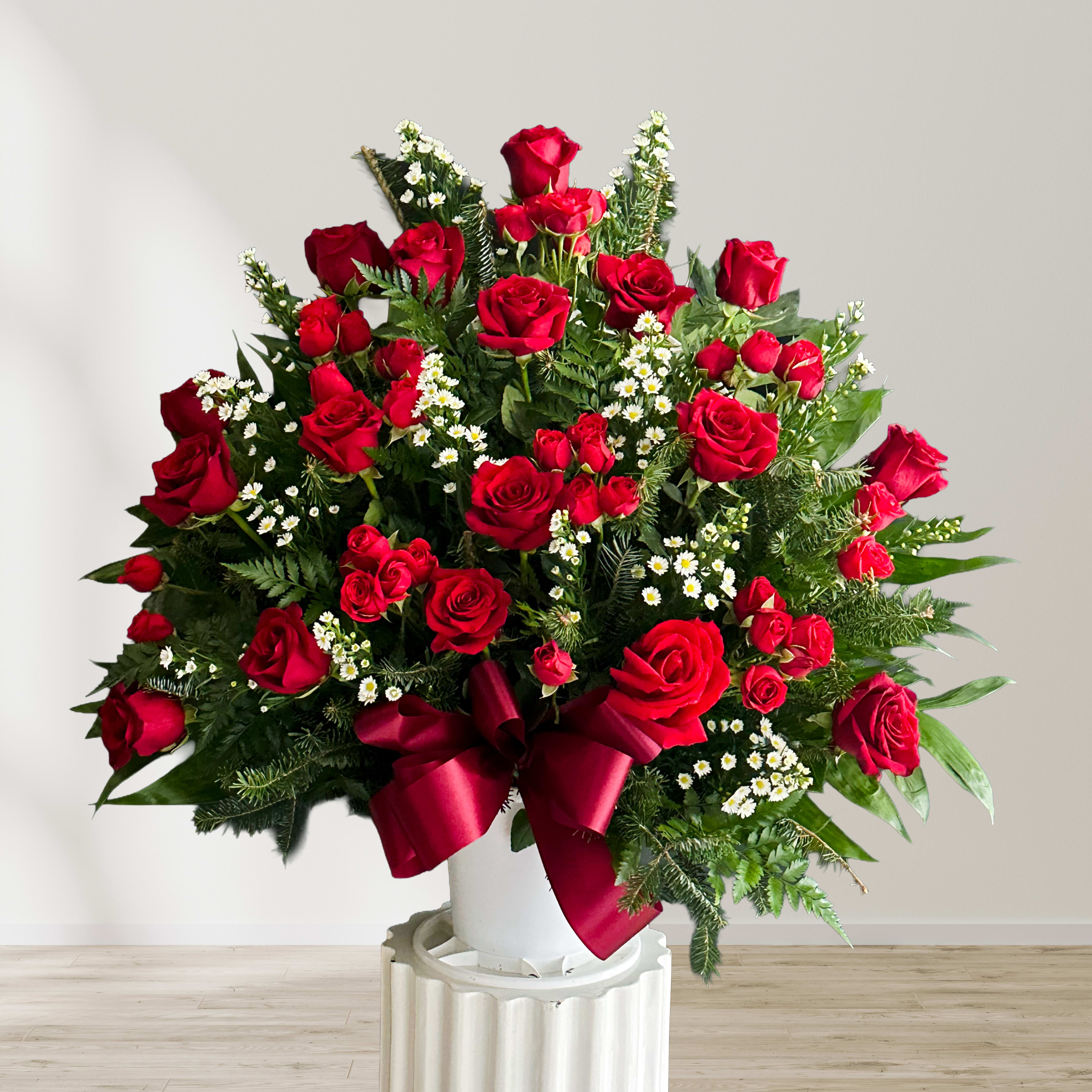 Large bouquet of red roses with white filler flowers in a white vase