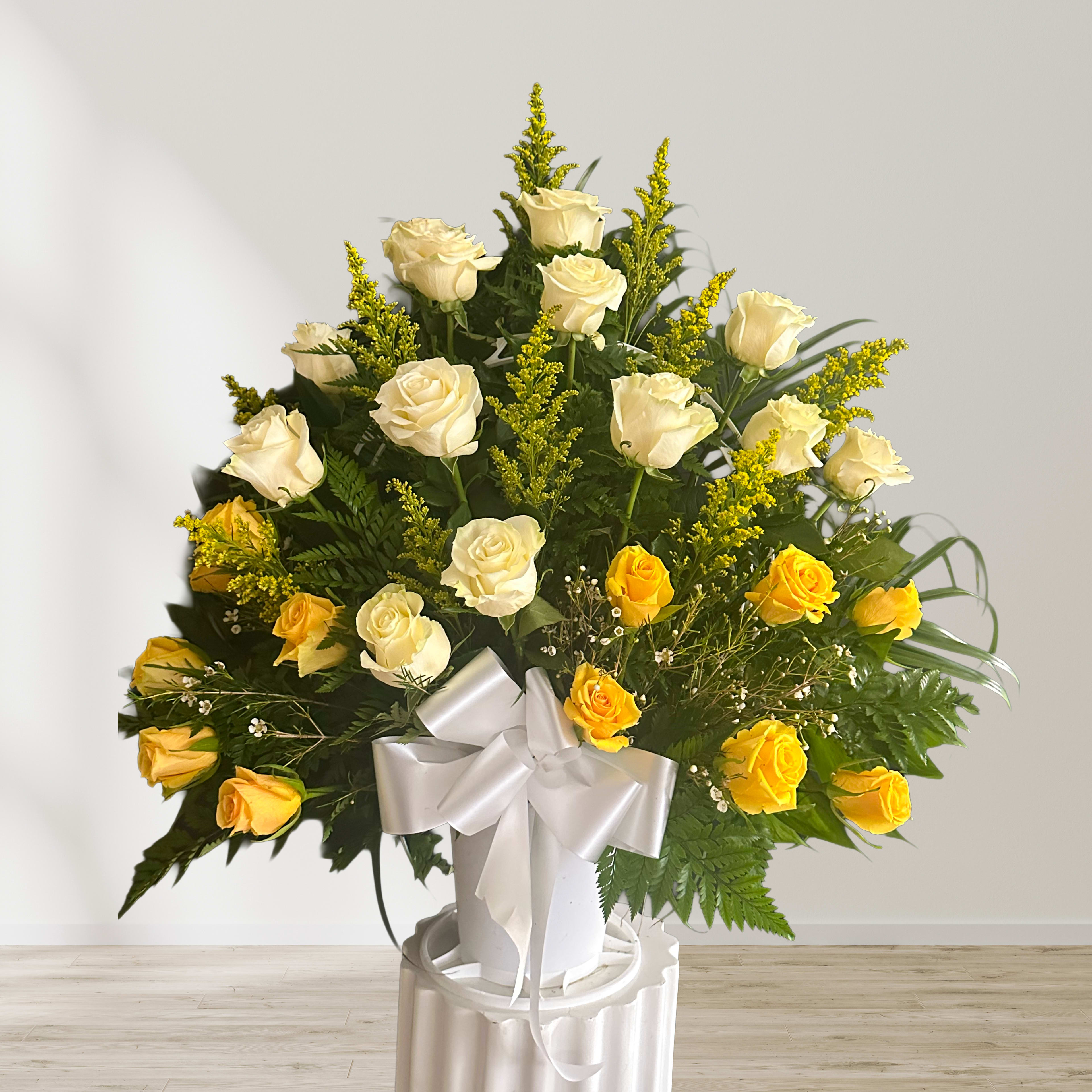 White and yellow roses in a white vase with a satin bow
