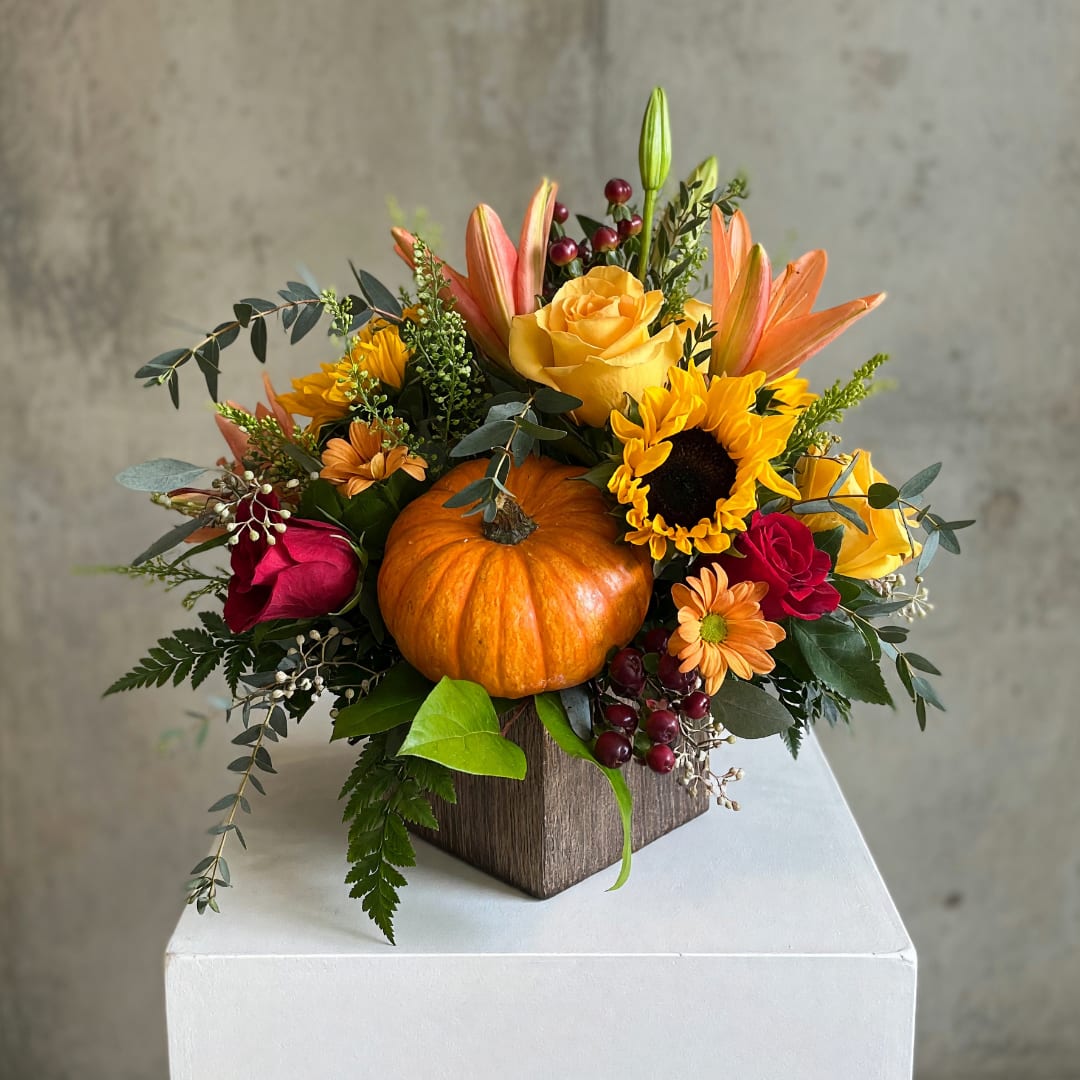 Autumn floral arrangement with a pumpkin centerpiece in a wooden box