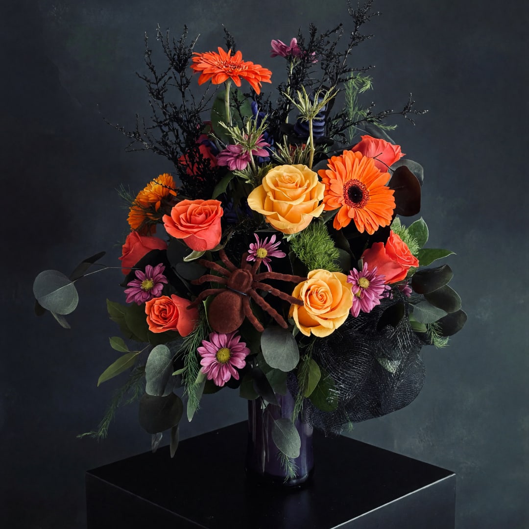 Bouquet of orange and pink flowers in a dark vase