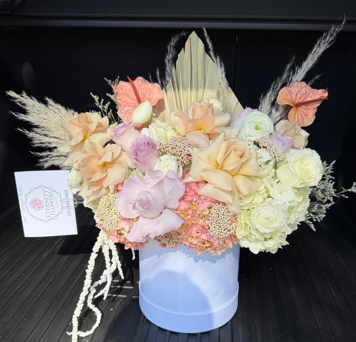 Pastel floral arrangement in a light blue box with pampas grass