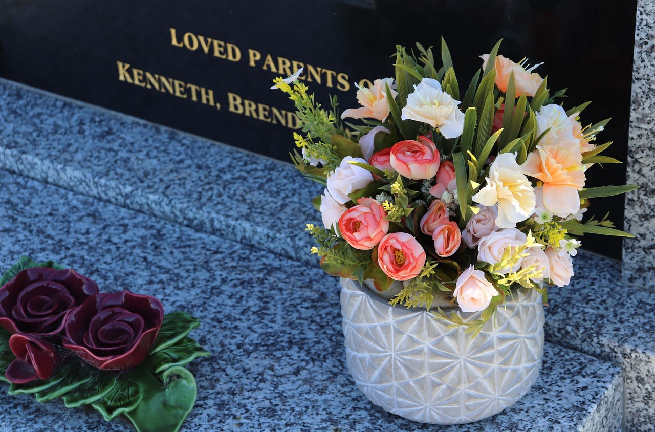 Mixed bouquet in a white textured vase beside a memorial plaque
