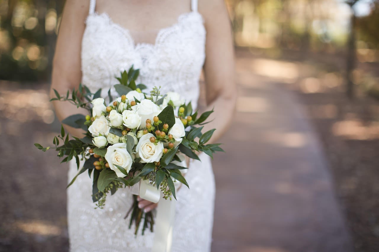 Bride holding a white rose bouquet with greenery