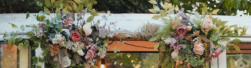 Floral garlands with pink and cream flowers drape over a white structure.