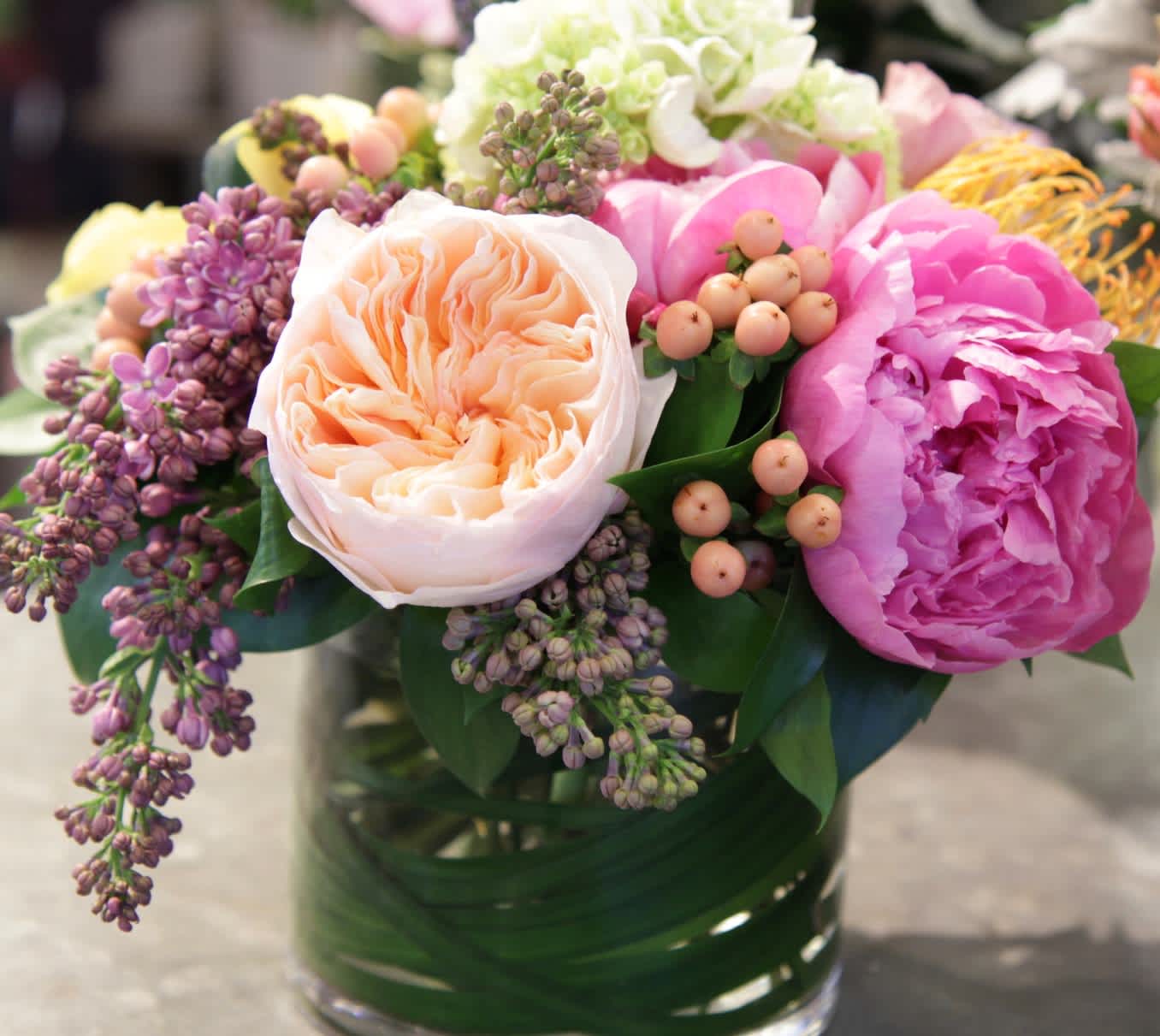 Mixed bouquet of pink, peach, and white flowers in a glass vase