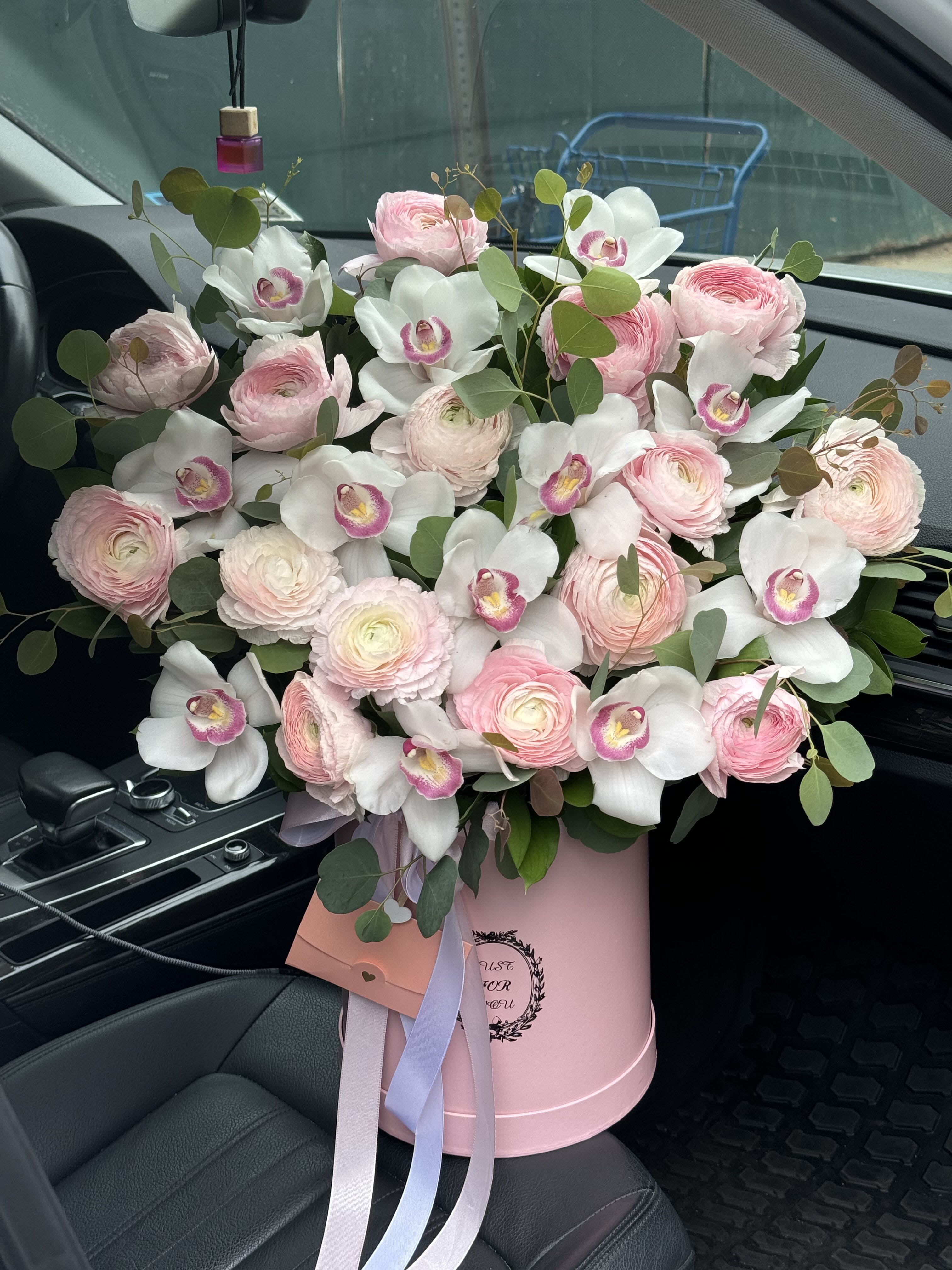 Pink ranunculus and white orchids in a pink hatbox